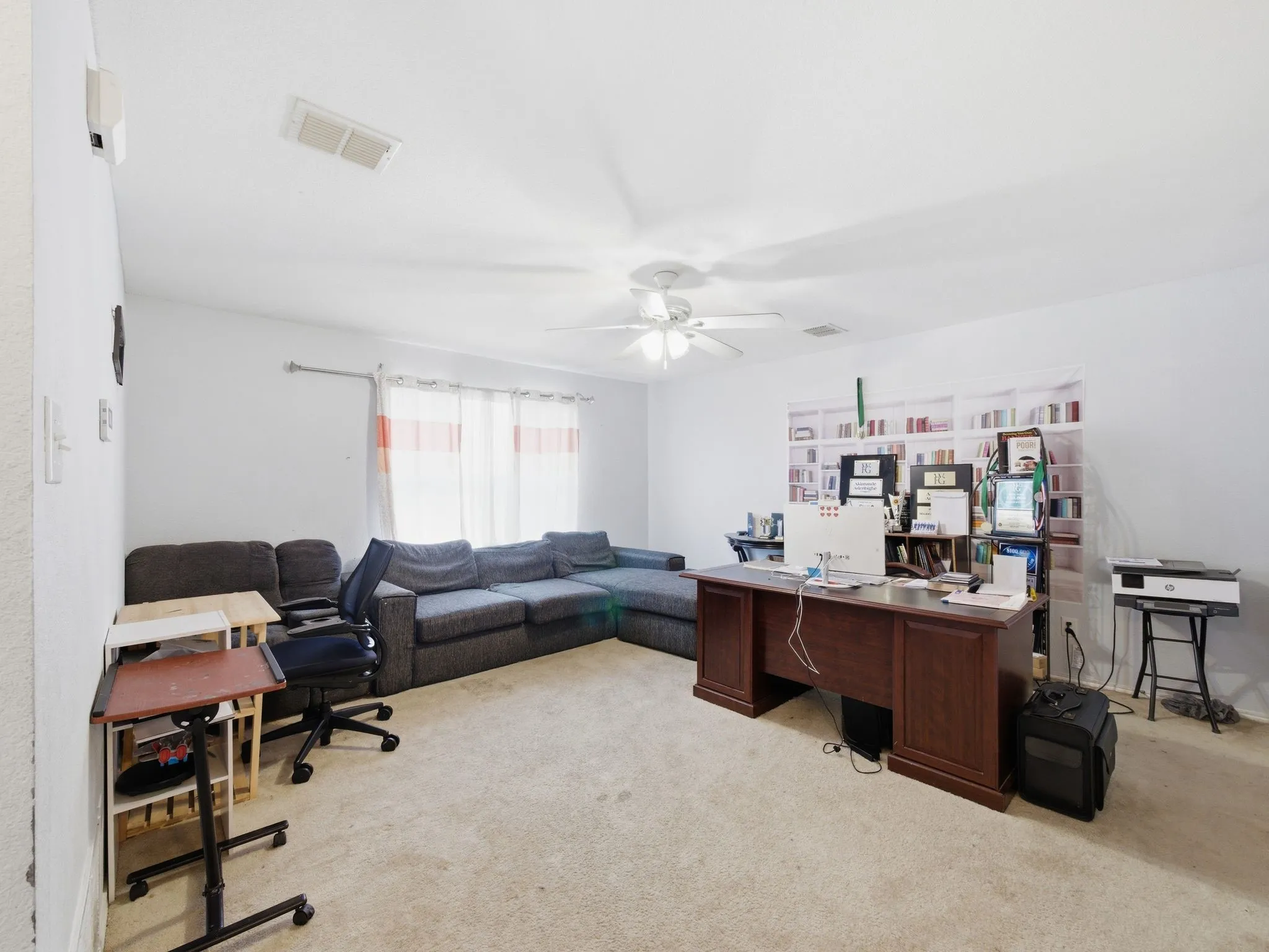Spacious room featuring light-colored carpeting, white walls, and a ceiling fan