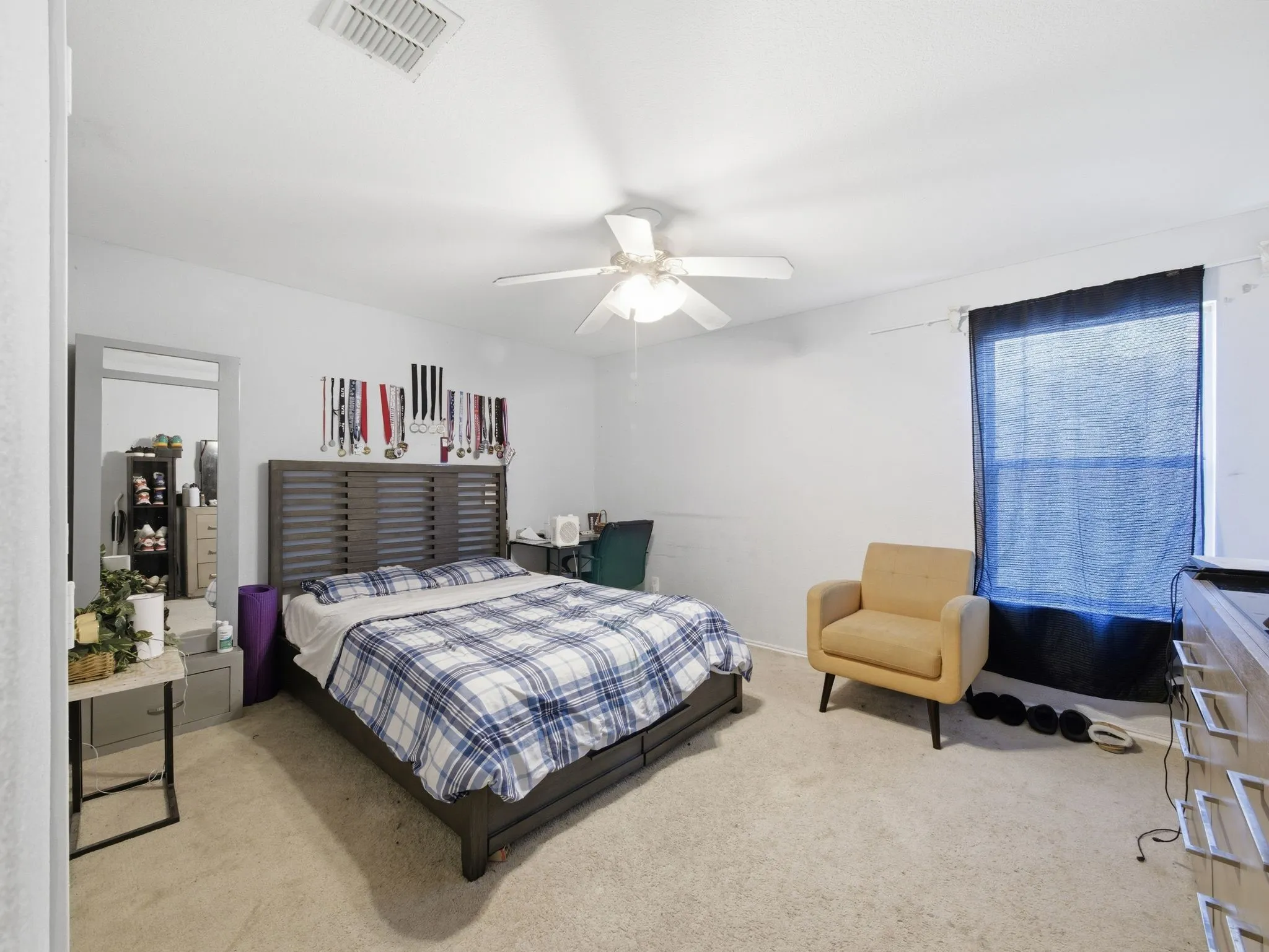 Spacious room featuring light-colored carpet flooring, a ceiling fan, and a single window with dark window treatments