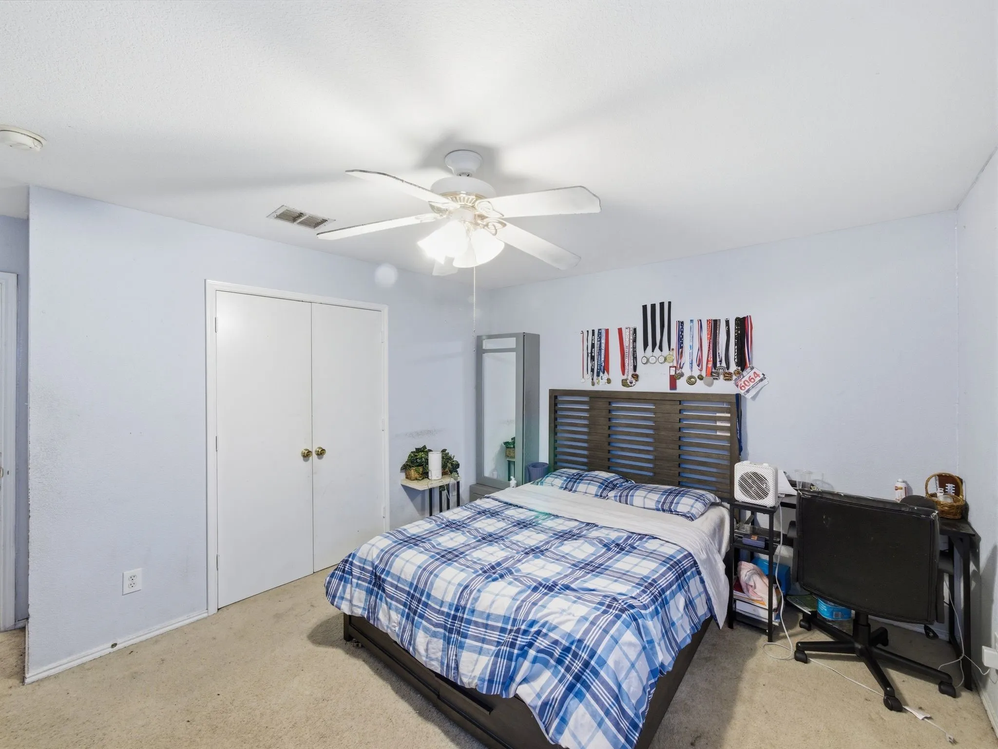Room featuring a ceiling fan, light-toned carpeting, and a double-door closet with brass hardware