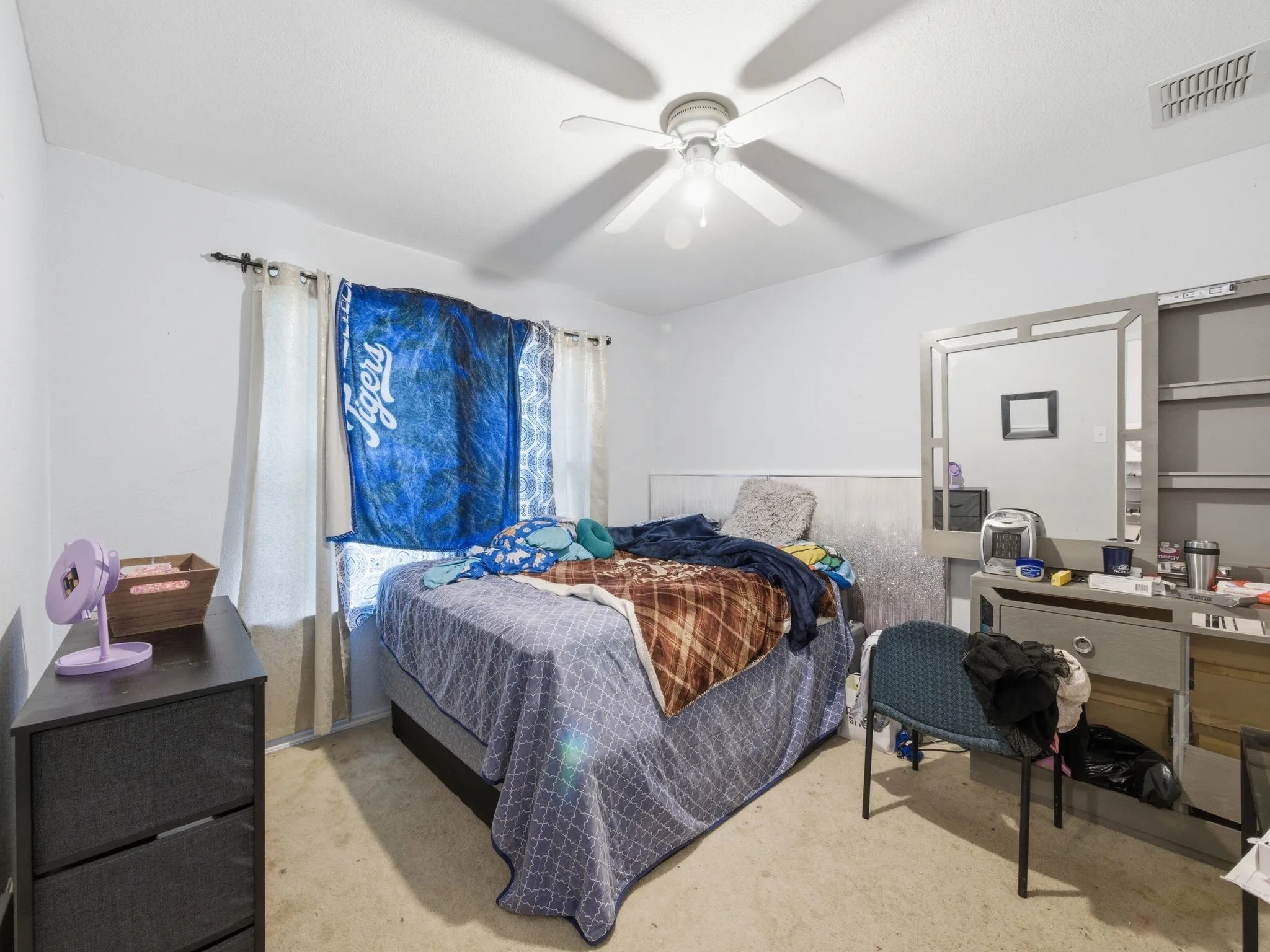 Bedroom featuring light-toned walls, a ceiling fan with integrated lighting, and carpeted flooring