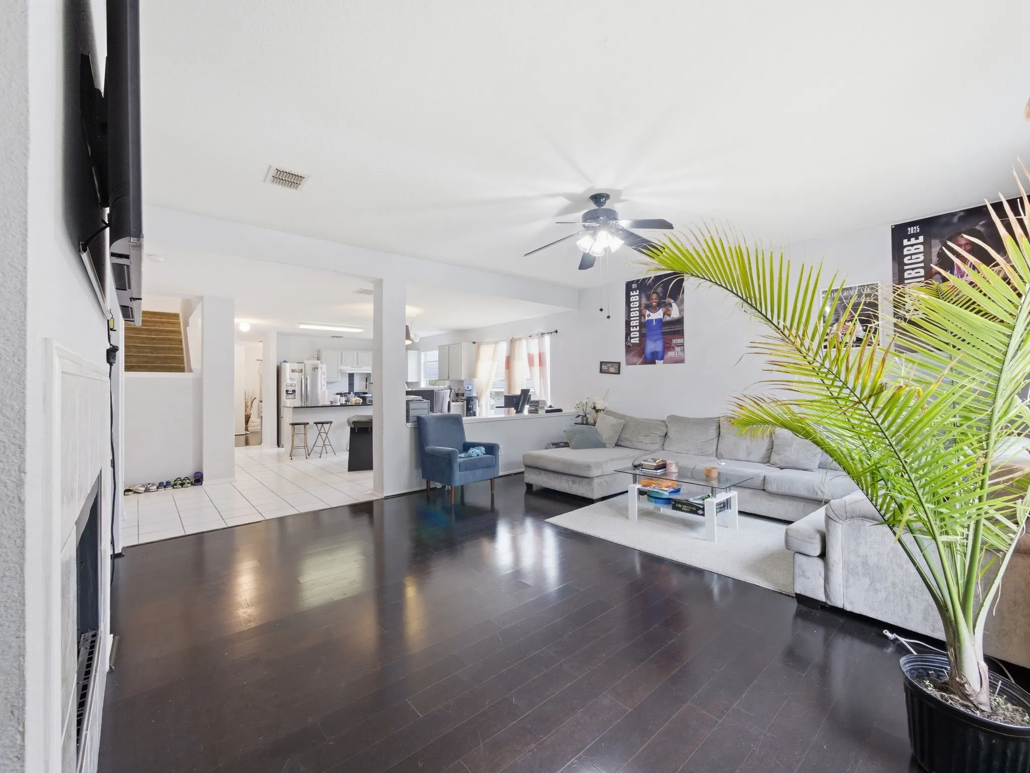 Spacious living area featuring dark wood-finish flooring, a ceiling fan, and white walls