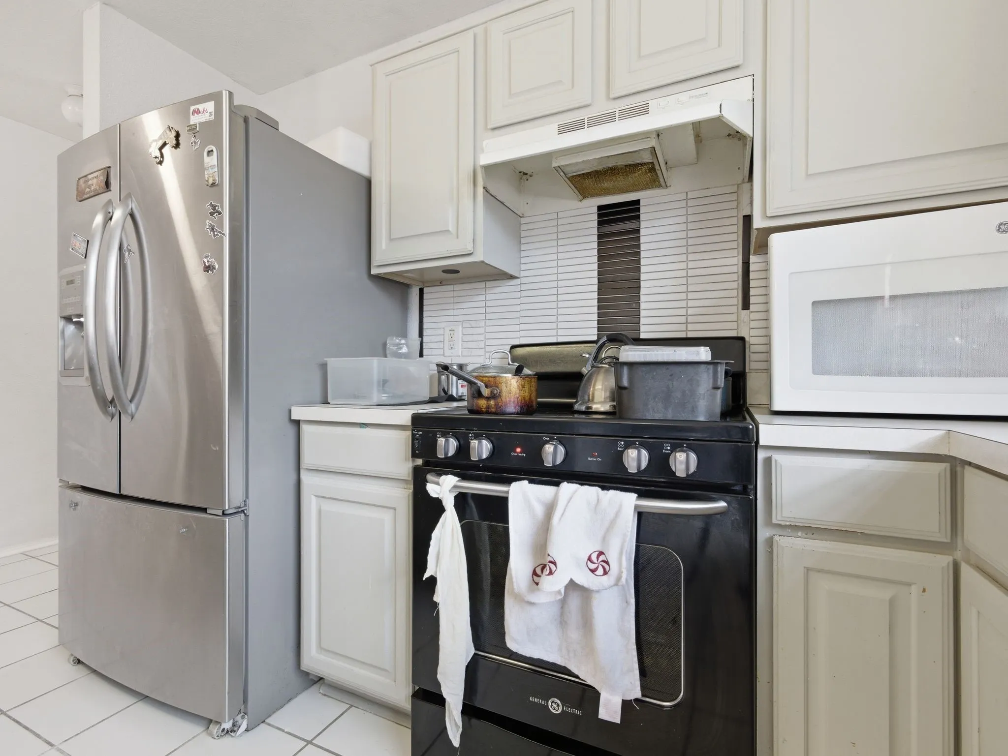 Kitchen featuring white panel cabinetry, a white tile backsplash, and white square tile flooring