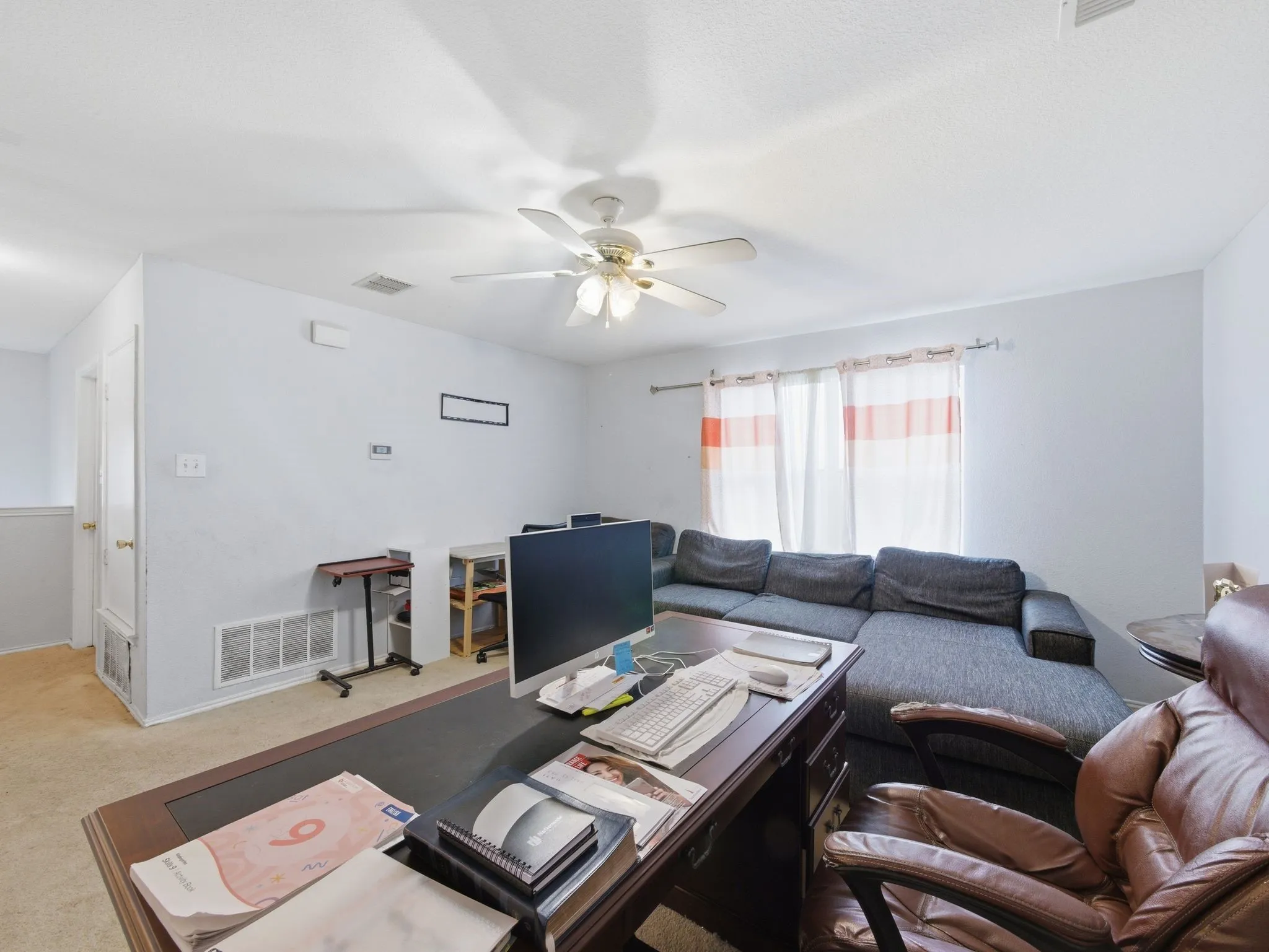 Open-concept space featuring light-colored carpeting and a ceiling fan
