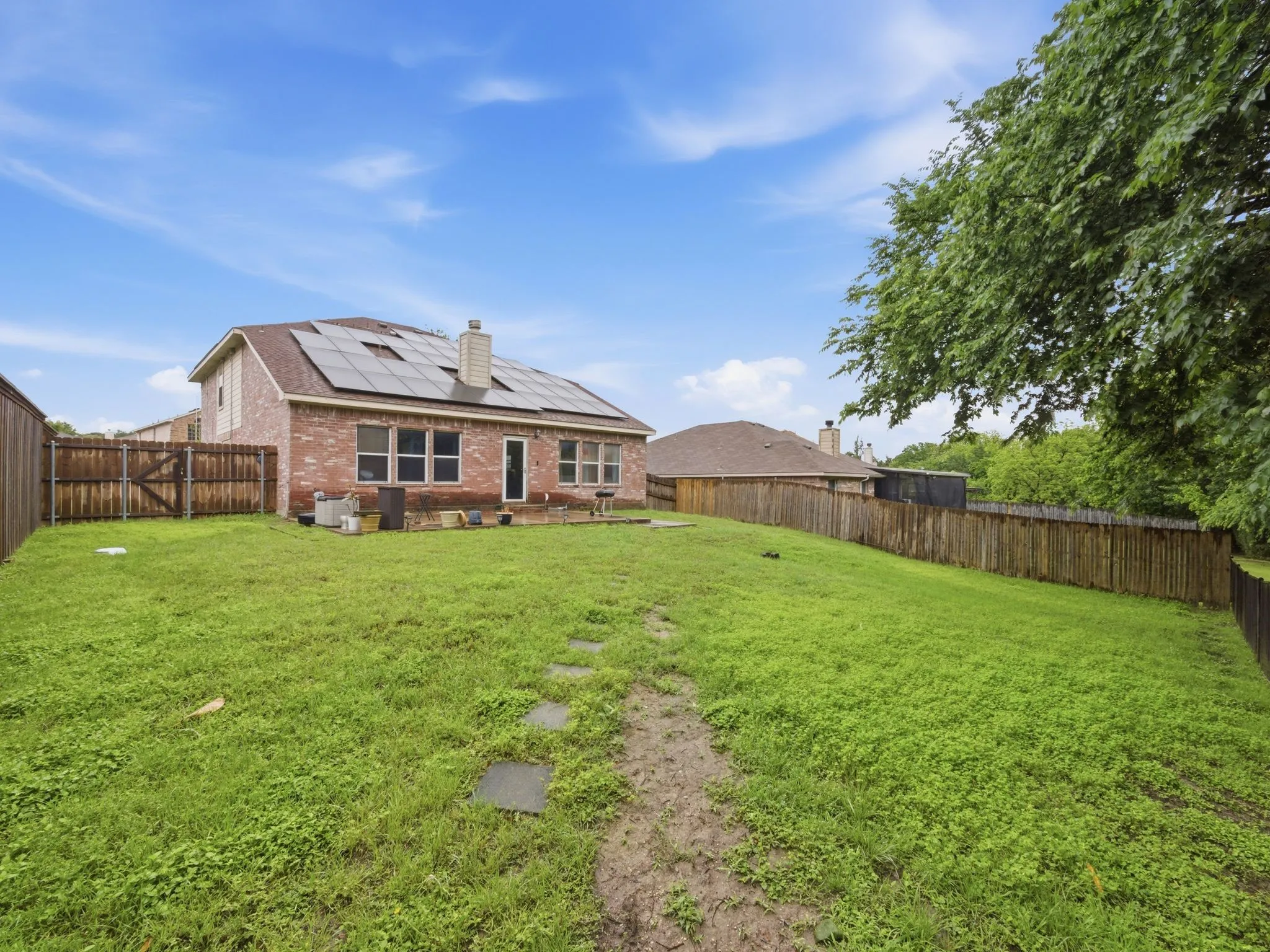 Spacious backyard featuring a brick exterior home with solar panels