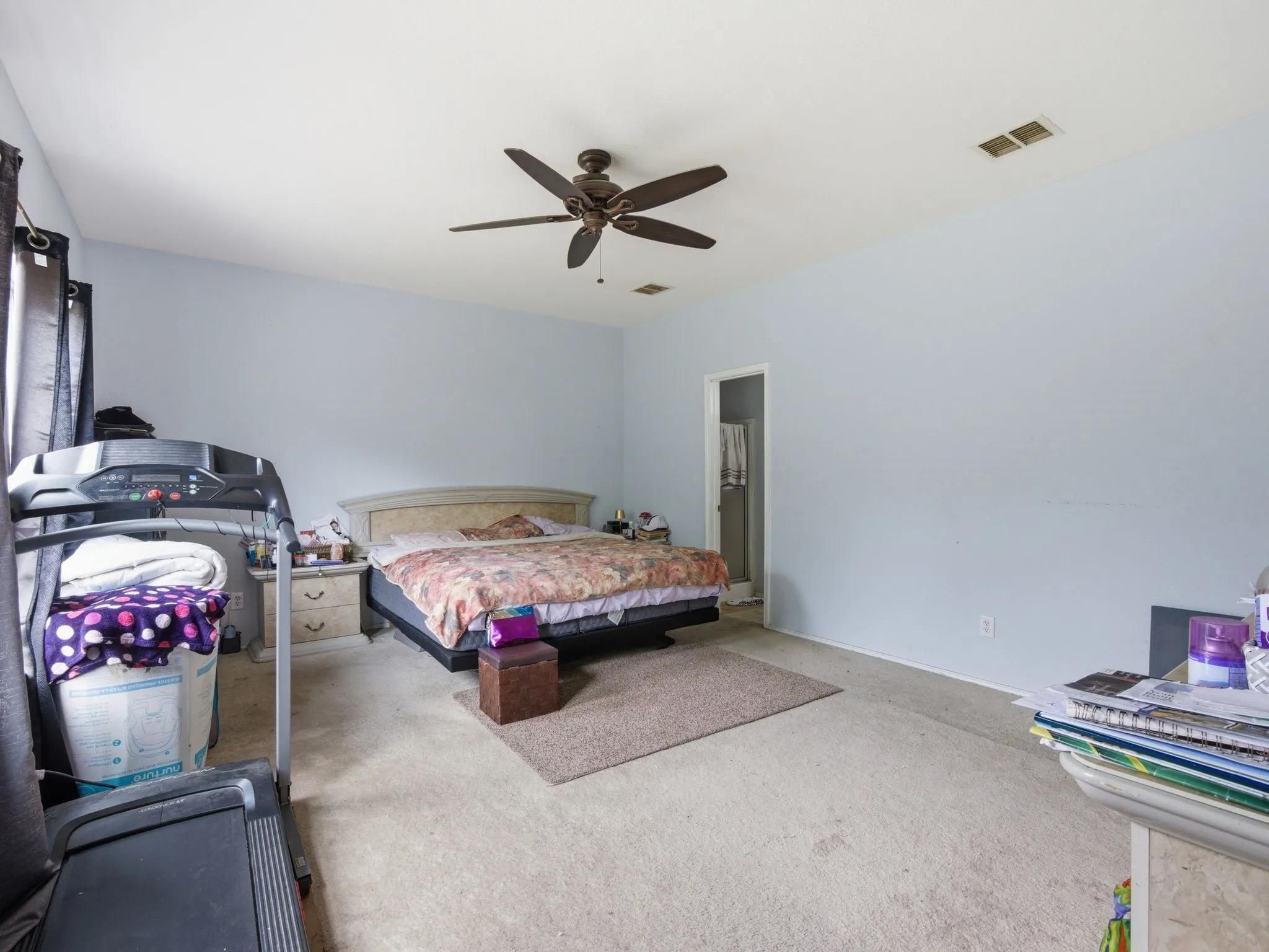 Spacious bedroom featuring light blue walls, neutral carpet, and a ceiling fan with integrated lighting