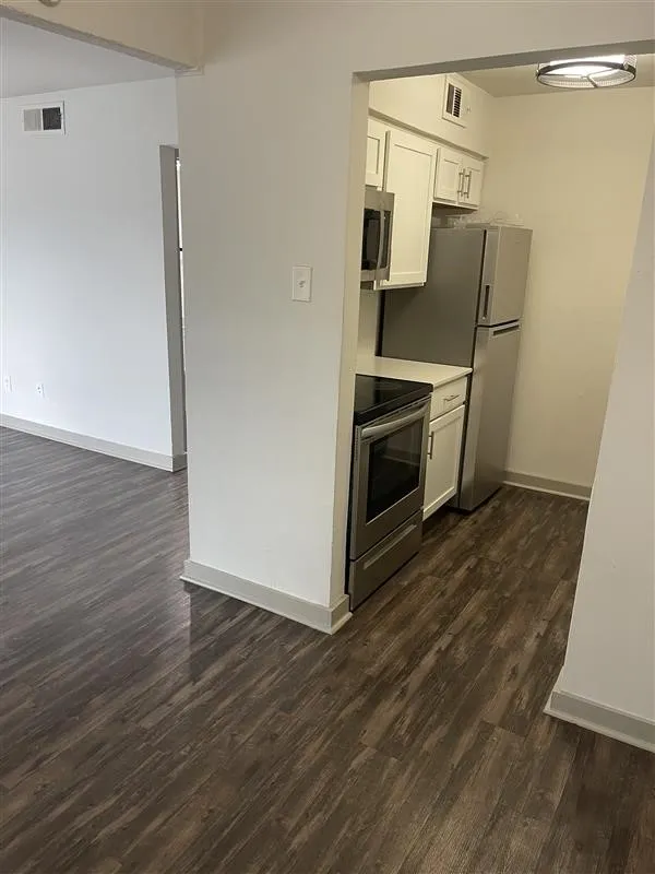Kitchen featuring stainless steel appliances, white cabinetry, and light countertops
