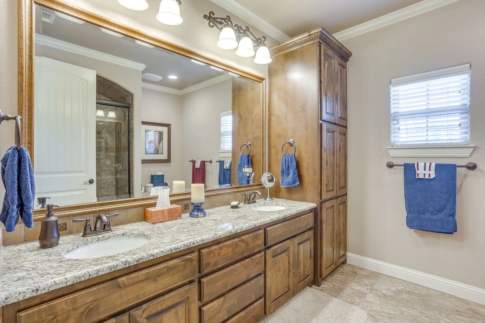 Double vanity with undermount sinks, stone-finish countertop, and wood-finish cabinetry
