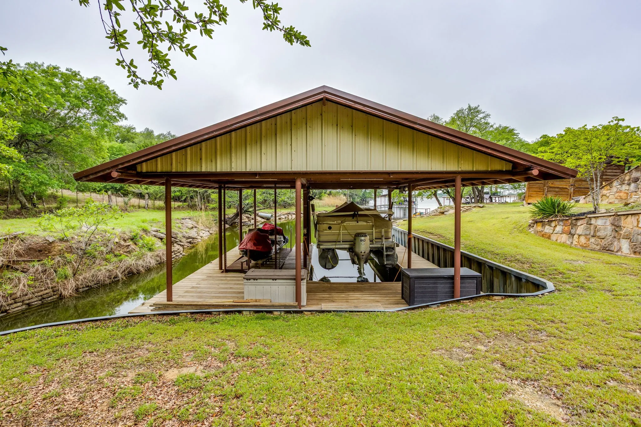 Covered boat dock featuring a metal roof, wood decking, and direct water access