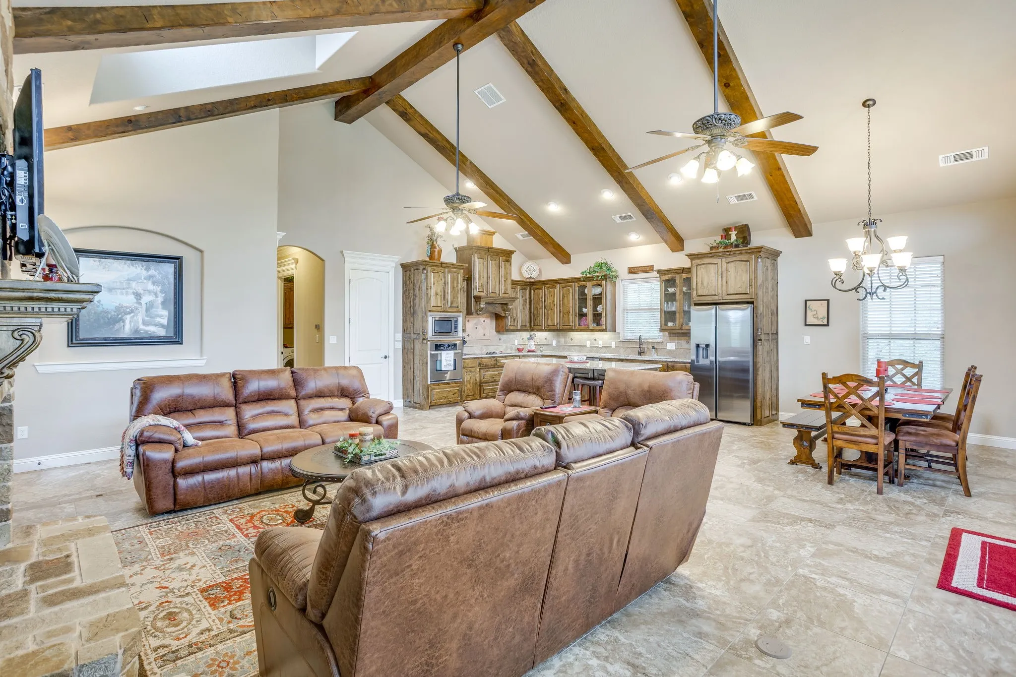 Expansive great room featuring a vaulted ceiling with exposed wood beams