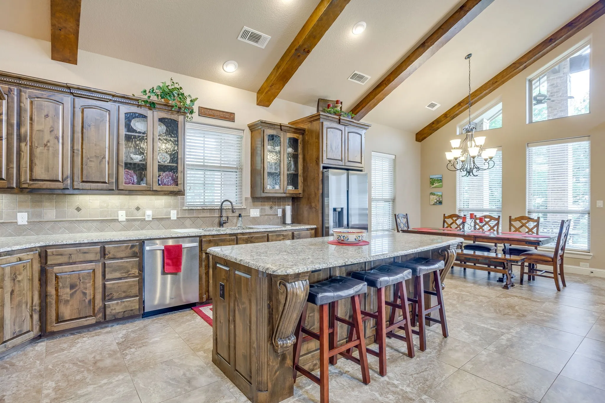 Open-concept kitchen and dining area featuring vaulted ceilings with exposed wood beams
