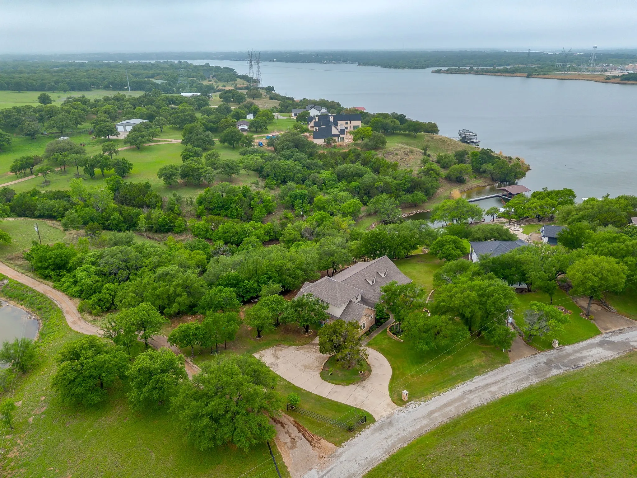 Expansive property featuring a circular driveway, mature trees, and a private pond