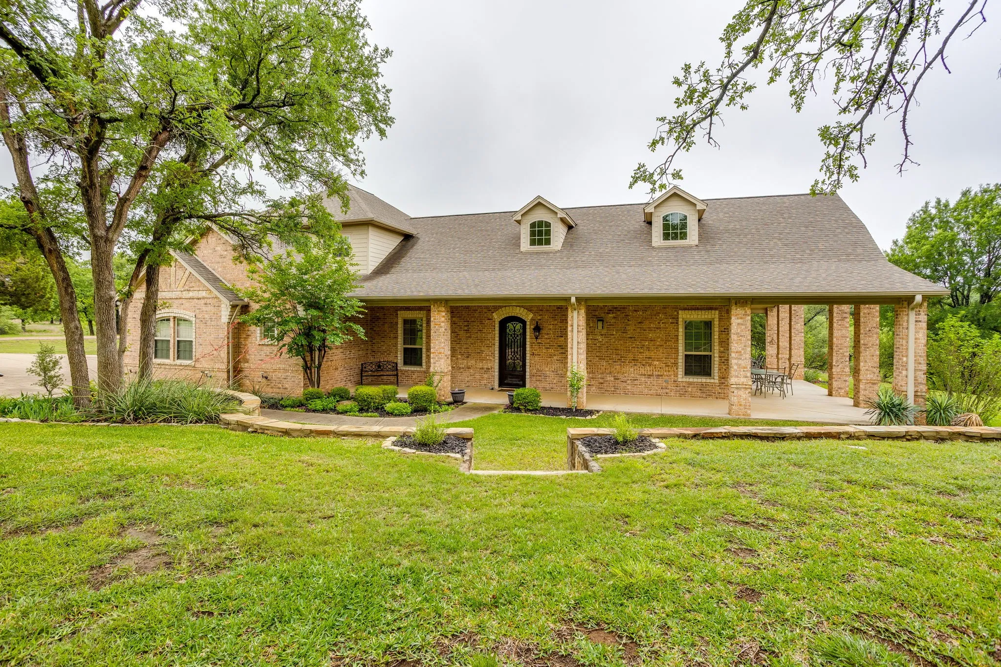 Brick exterior featuring a covered front porch with stone columns