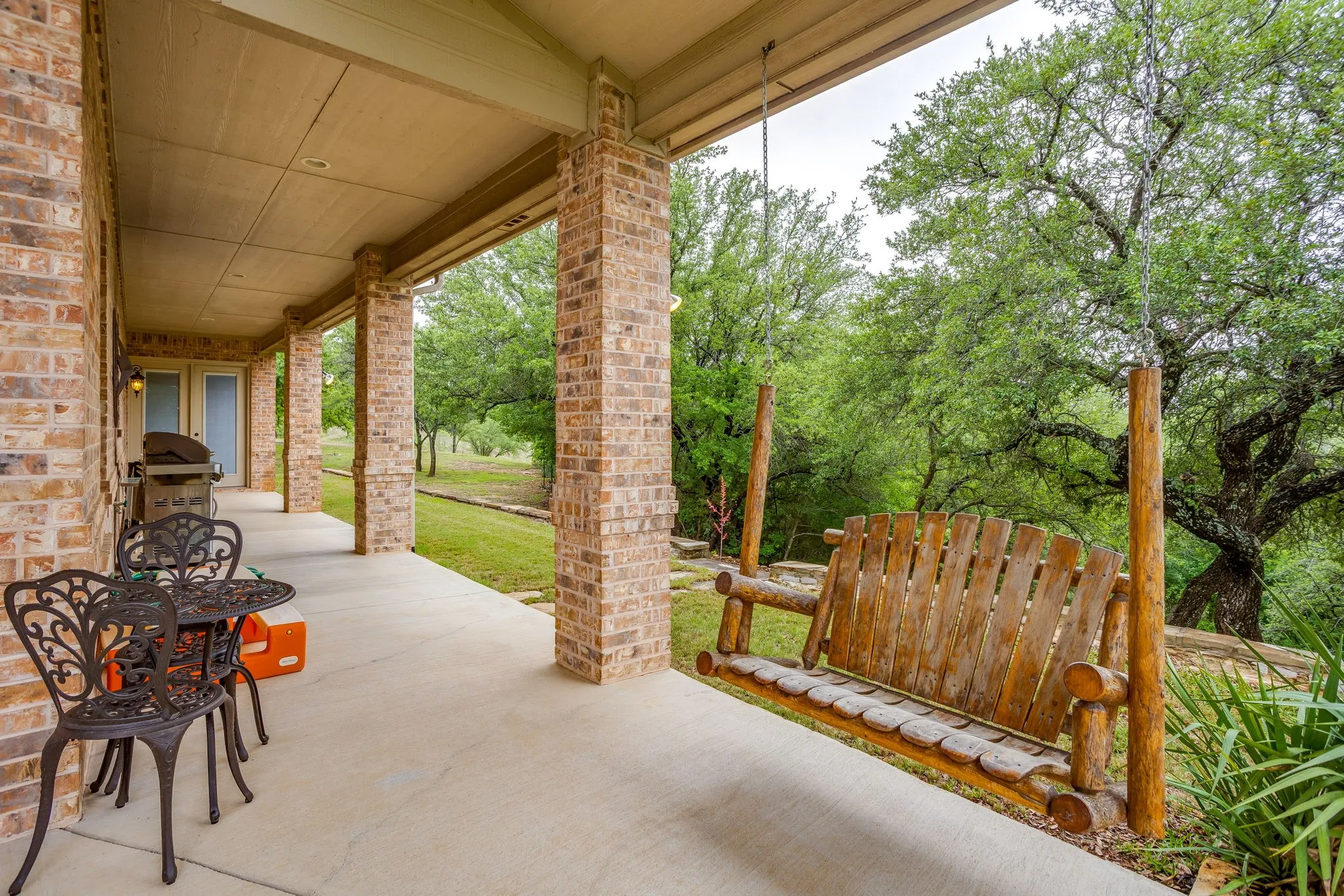 Expansive covered patio featuring brick columns and a concrete surface