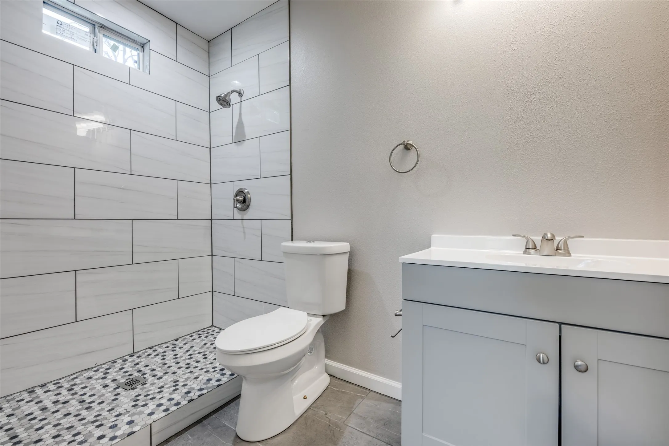 Full bathroom with vanity, a tile shower, and tile patterned floors
