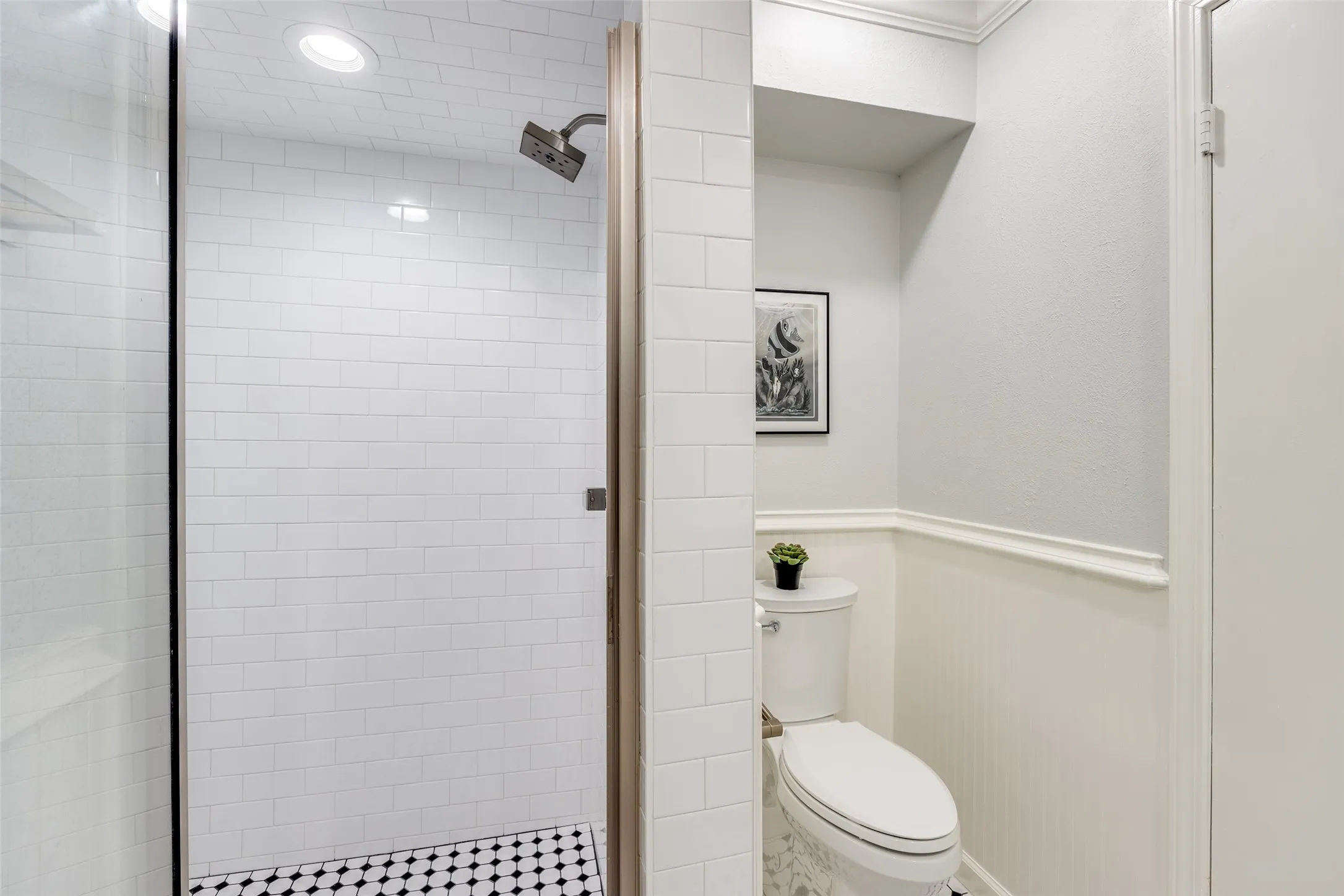 Walk-in shower with subway tile surround and black and white penny tile flooring