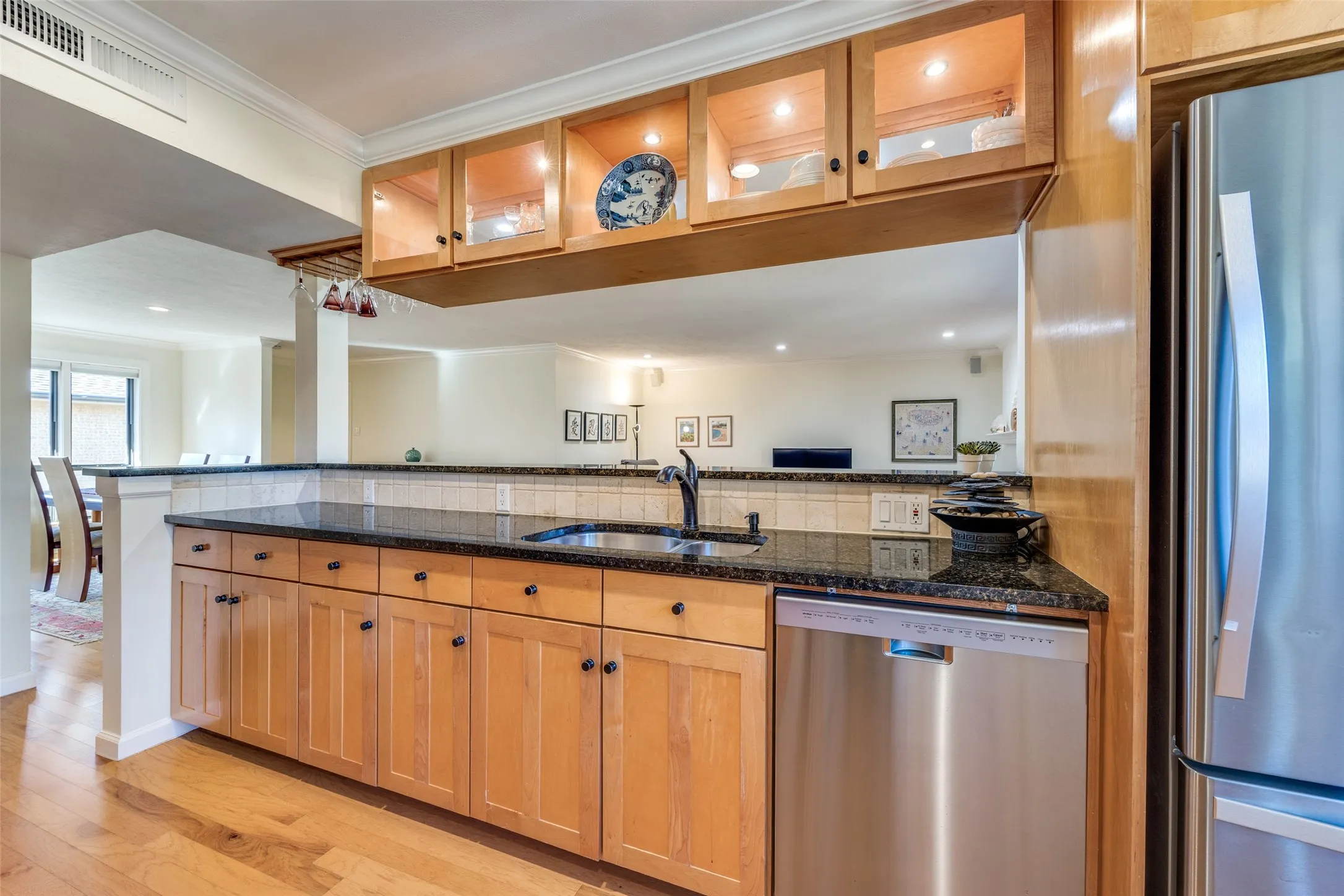 Kitchen featuring wood-finish cabinetry, dark countertops, stainless steel appliances, and a tile backsplash