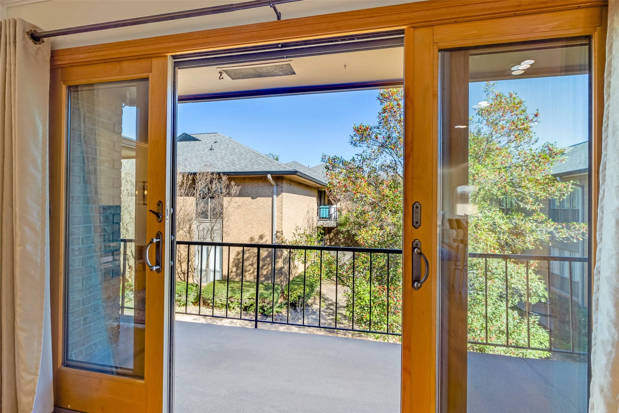 Sliding glass patio doors with wood-finish frames opening to a private balcony
