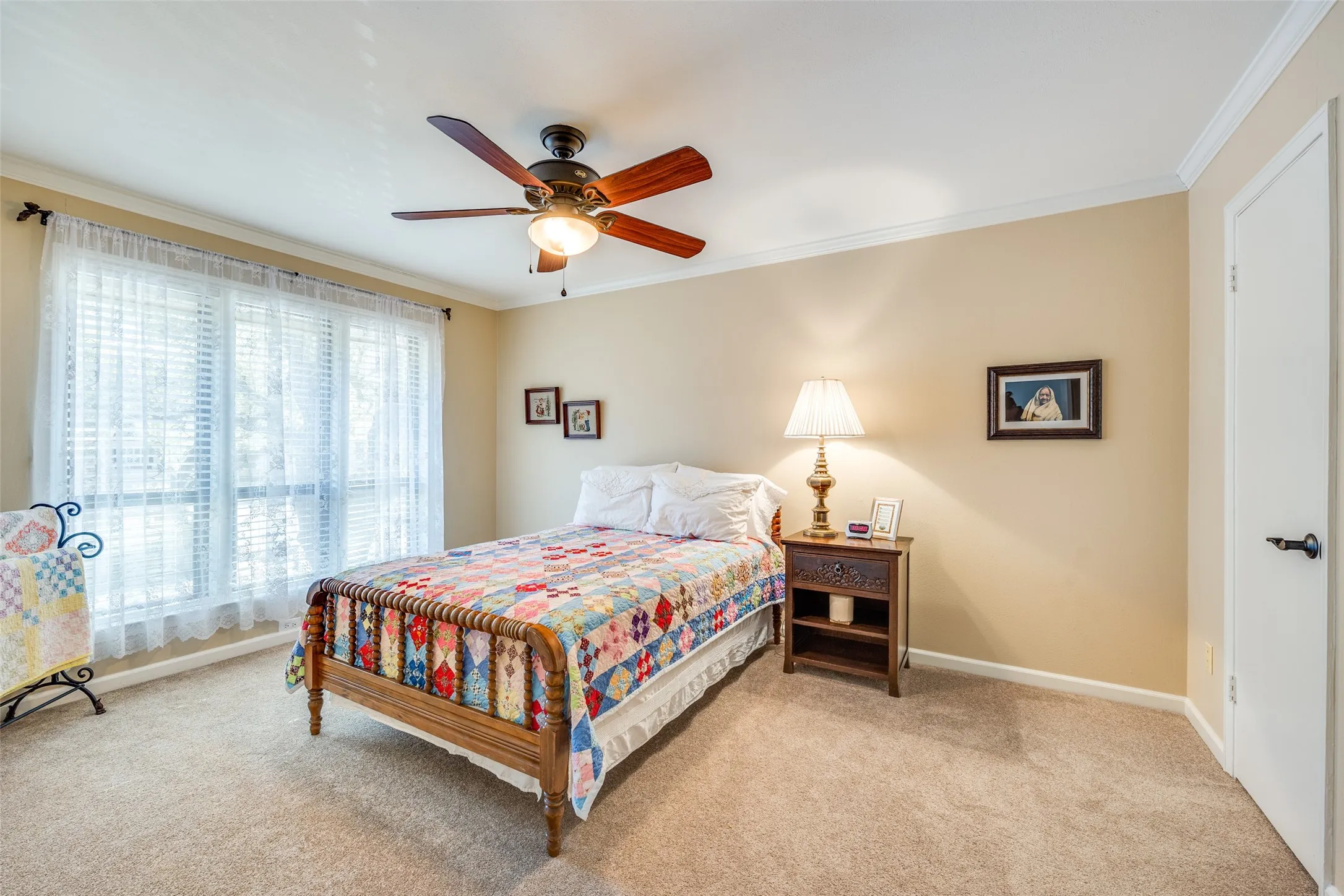 Generously sized window featuring white blinds and sheer curtains