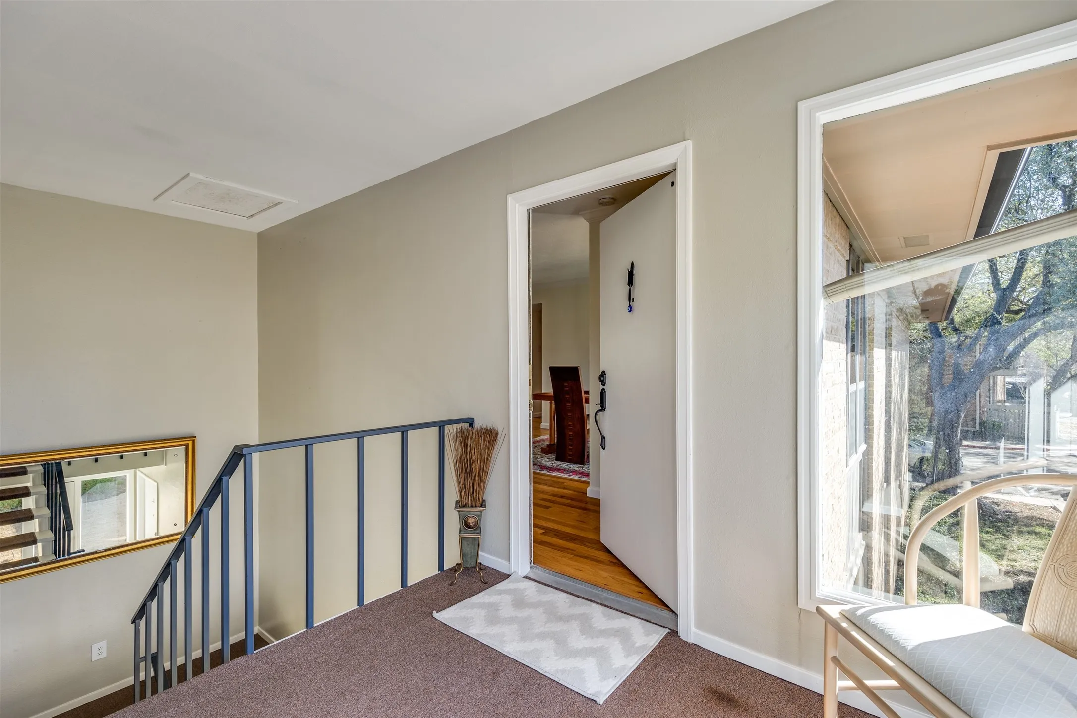 Entryway featuring a white front door, a large window, a metal railing, and carpeted flooring