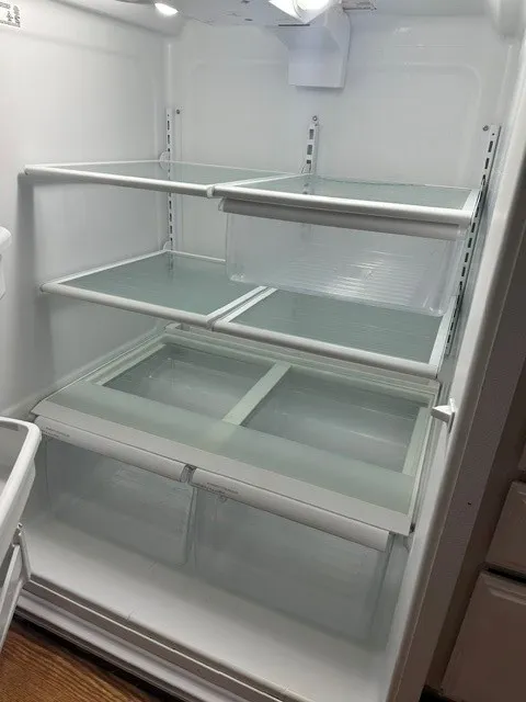 Integrated refrigerator interior featuring multiple glass shelves, clear crisper drawers, adjustable shelving racks, and interior lighting