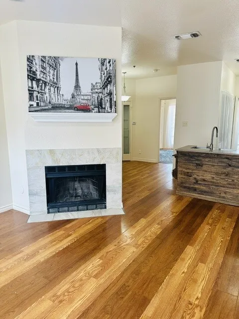 Hardwood flooring throughout, complemented by a stone-surround fireplace with a white mantel