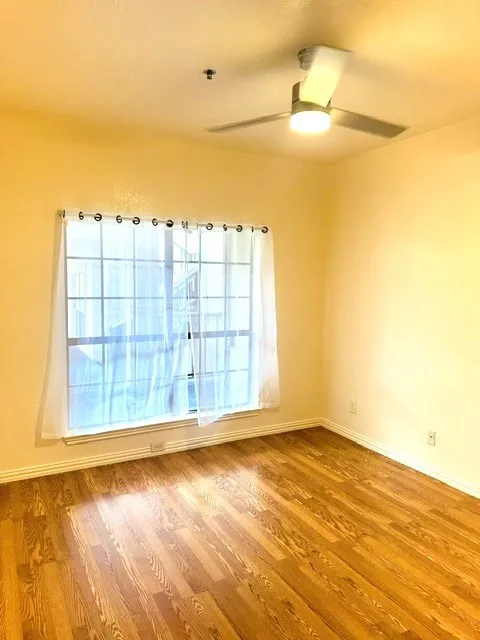 Hardwood flooring throughout featuring a window with white trim