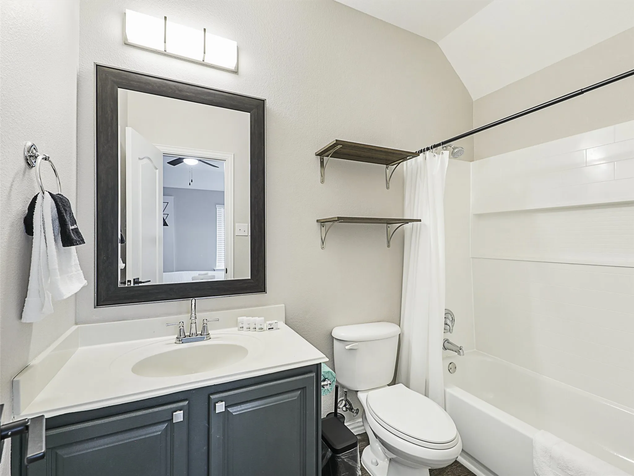 Bathroom featuring a vanity with a white countertop and dark gray cabinetry, a framed mirror, and a wall-mounted light fixture