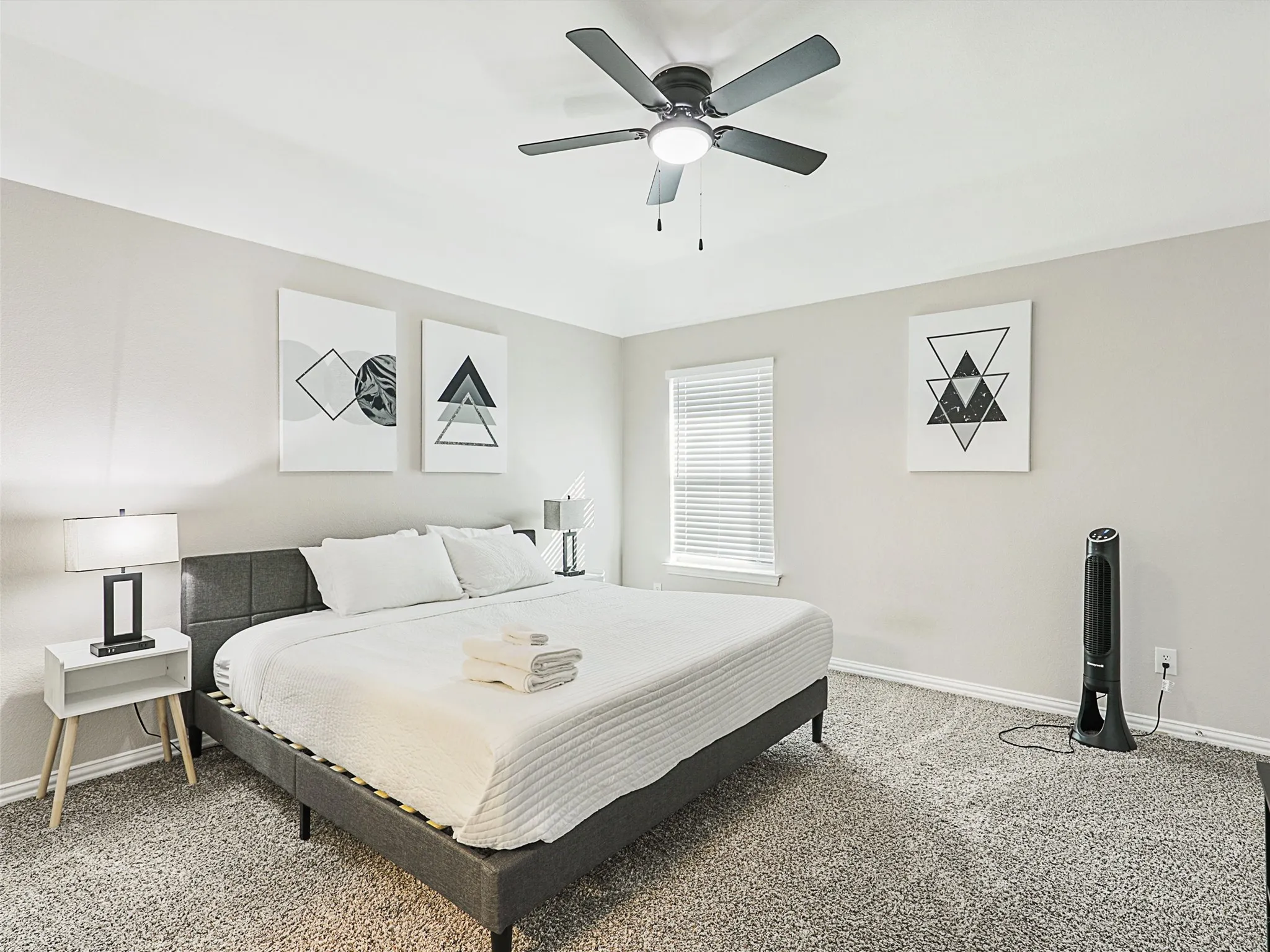 Carpeted bedroom featuring a ceiling fan with integrated lighting, a window with horizontal blinds, and neutral wall tones