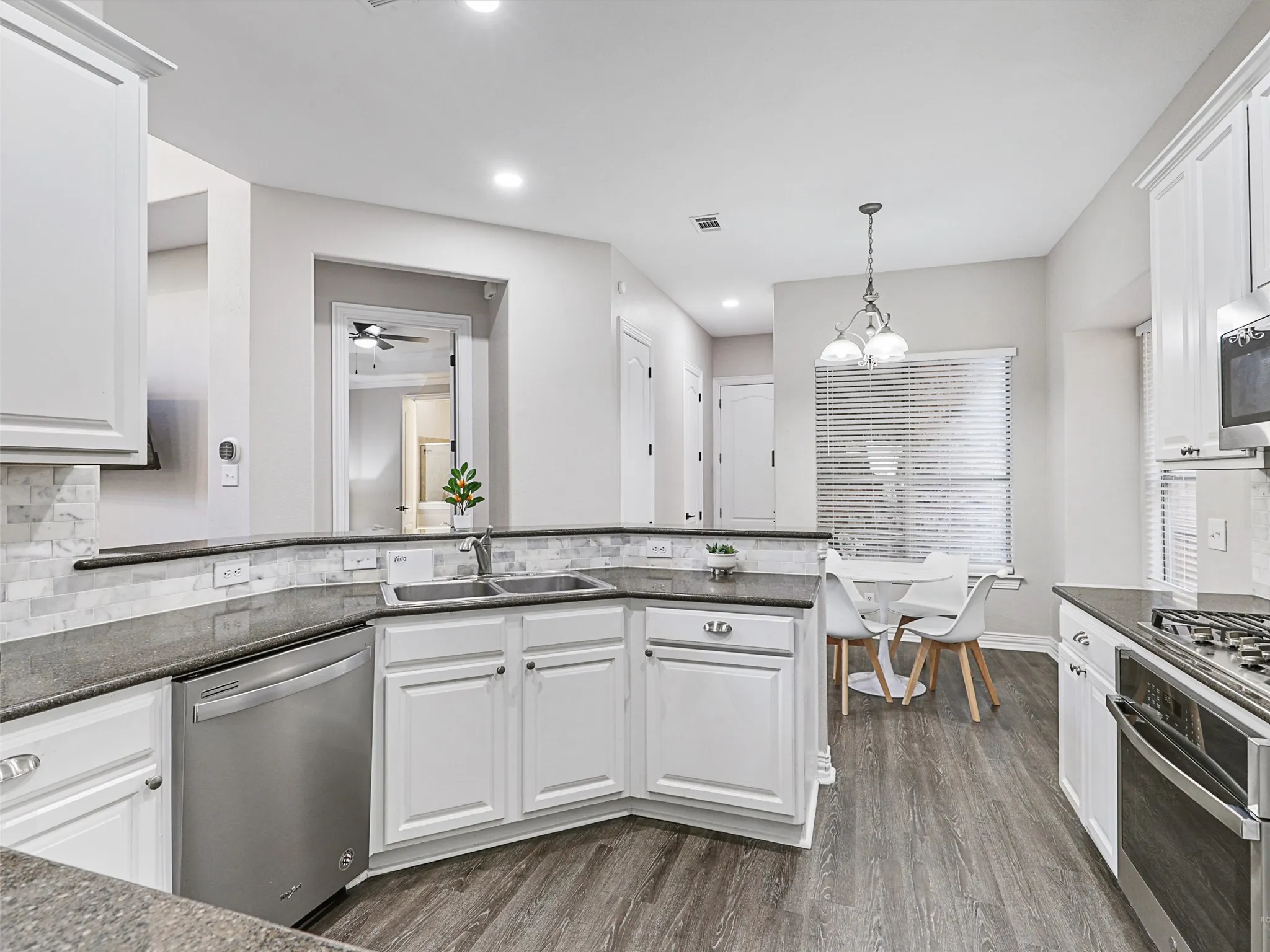 Modern kitchen featuring white cabinetry, dark countertops, and a full suite of stainless steel appliances