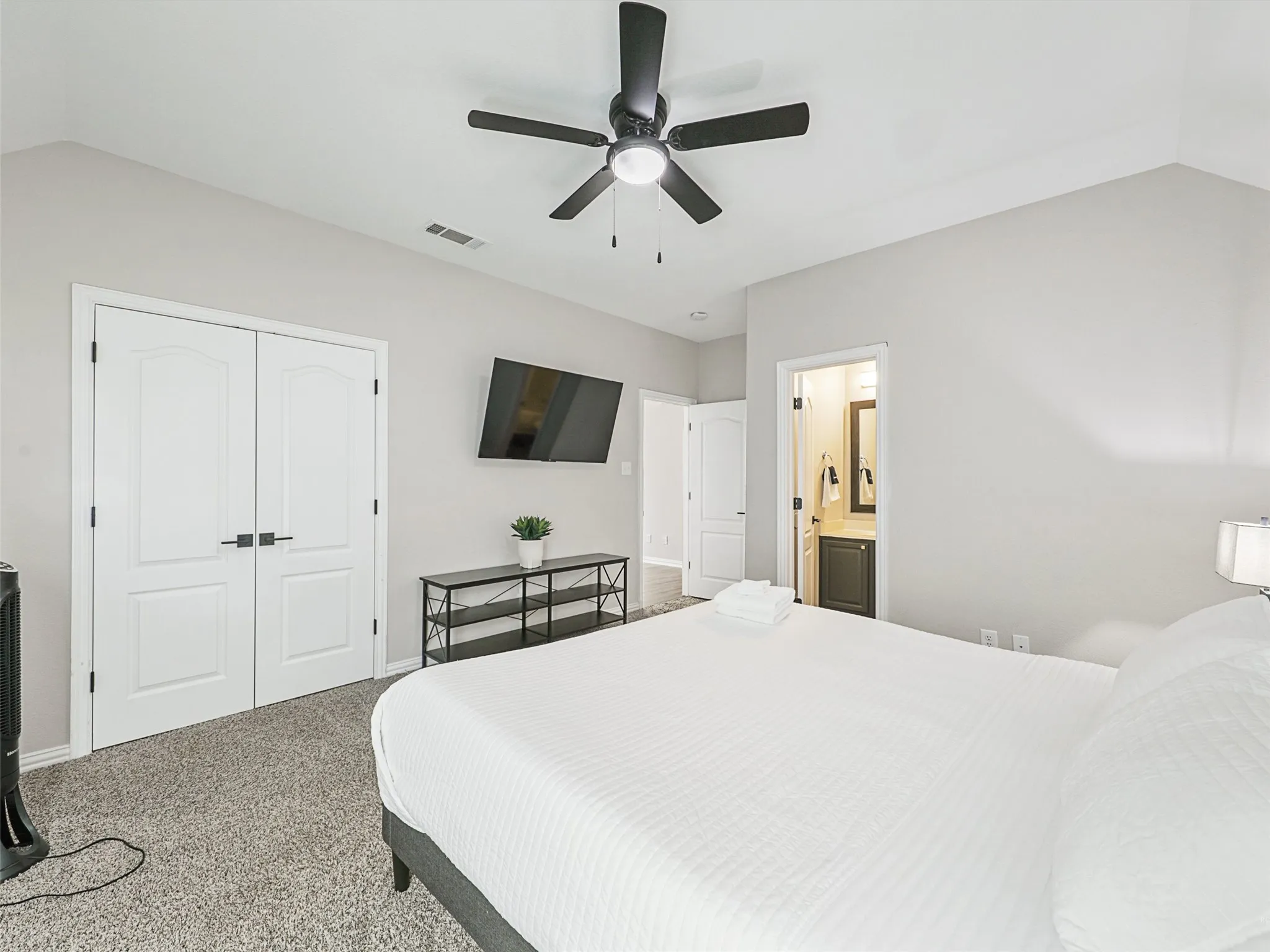 Bedroom featuring a vaulted ceiling with a black ceiling fan, gray carpet flooring, and white double doors