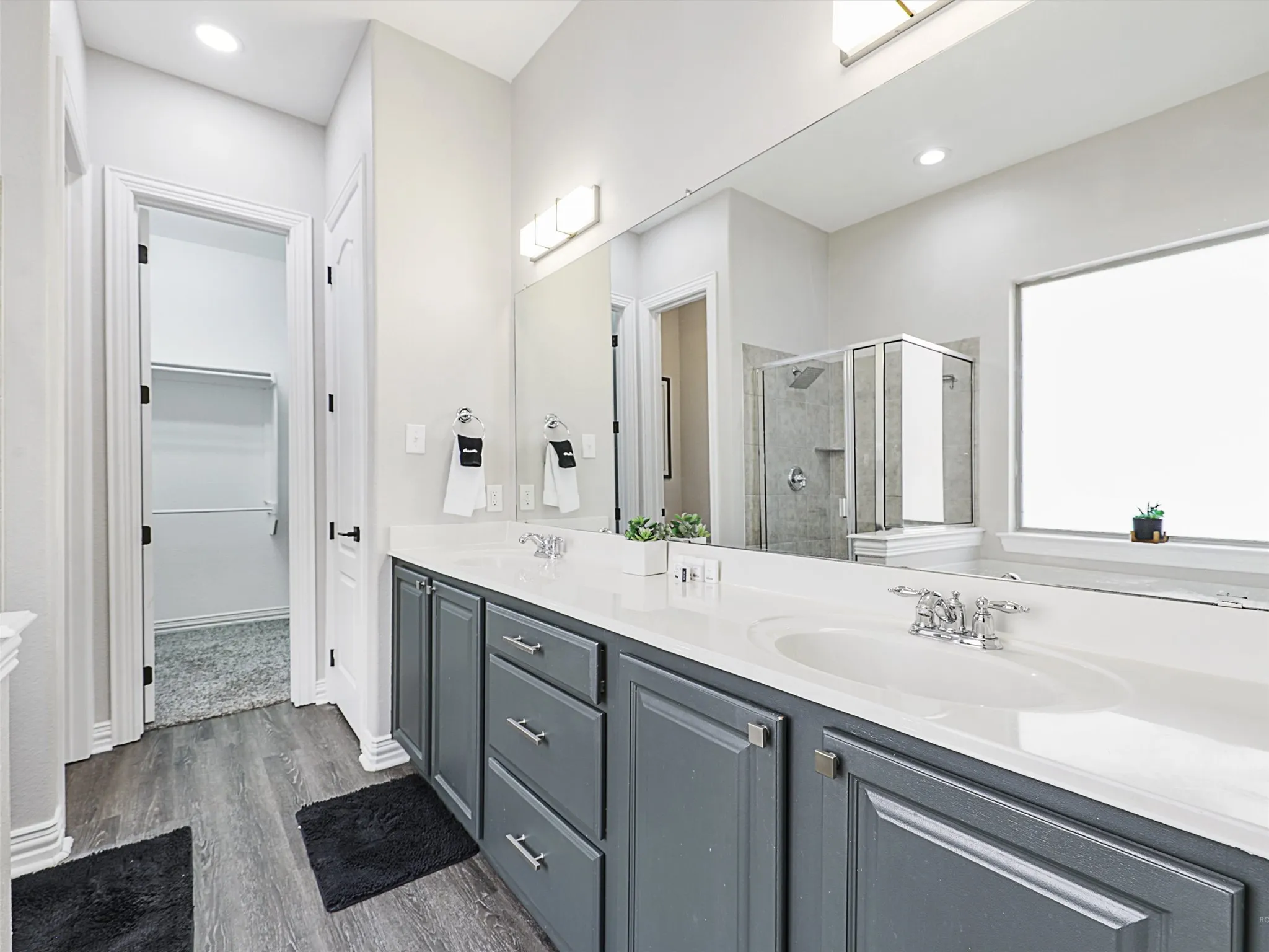 Bathroom vanity featuring dual sinks, gray cabinetry, and a large wall-mounted mirror