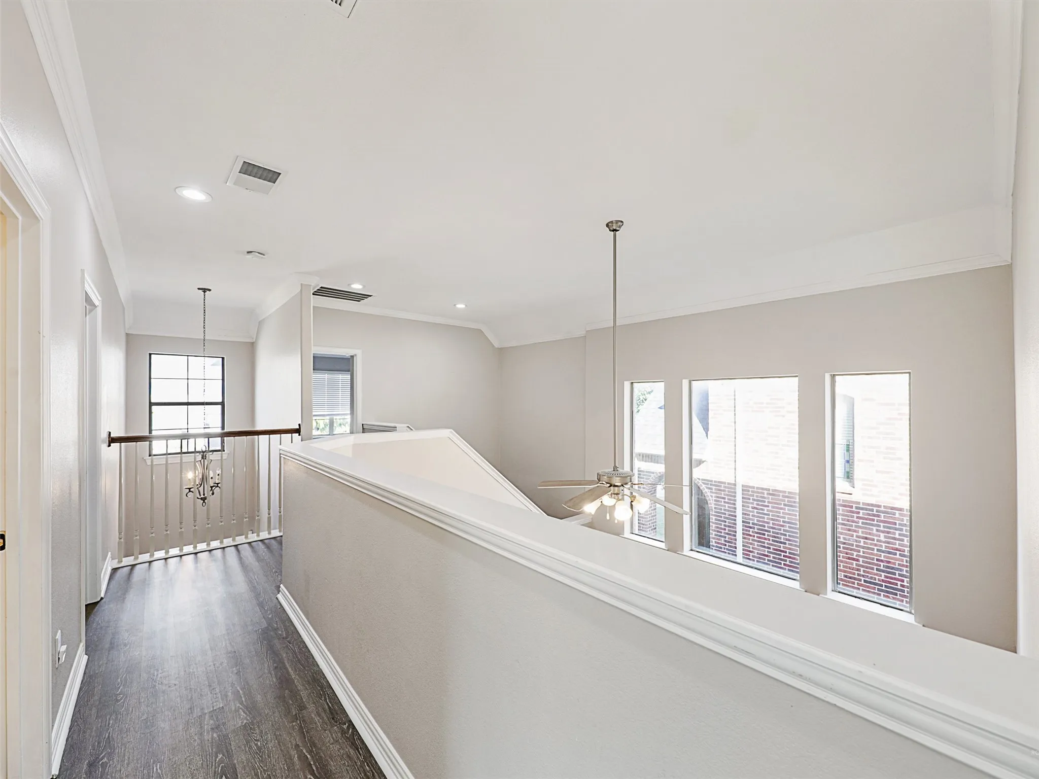 Upper-level landing featuring wood-finish flooring, white crown molding, and recessed lighting