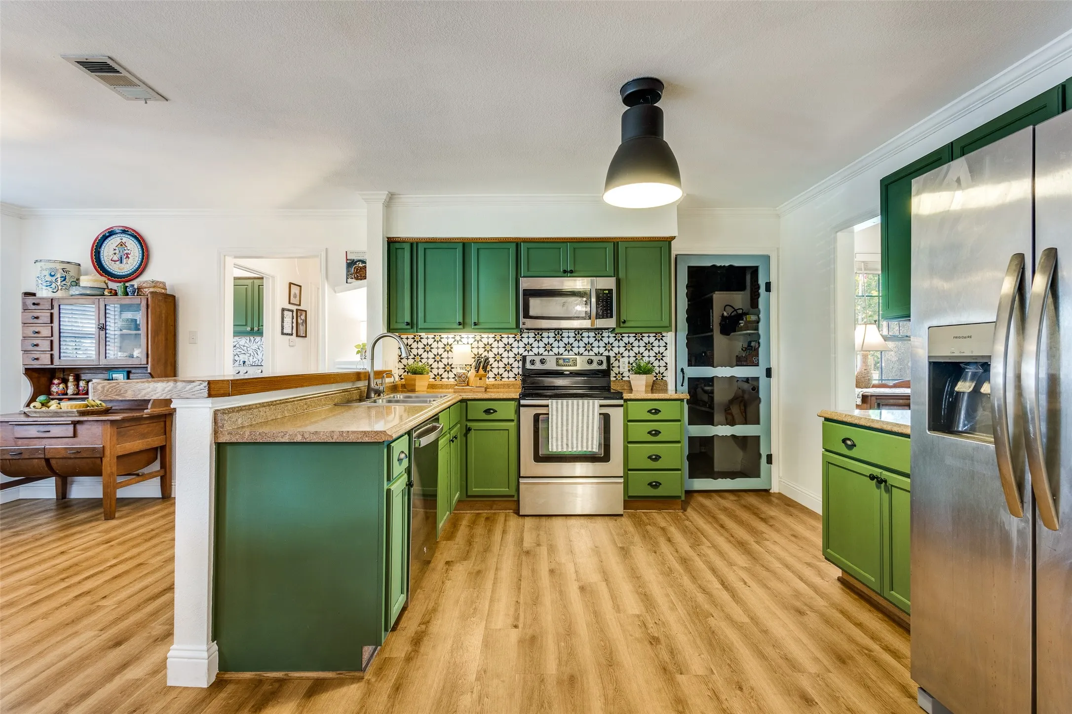 Updated kitchen is equipped with SS appliances, decorative backsplash, new lighting, and a walk-in pantry
