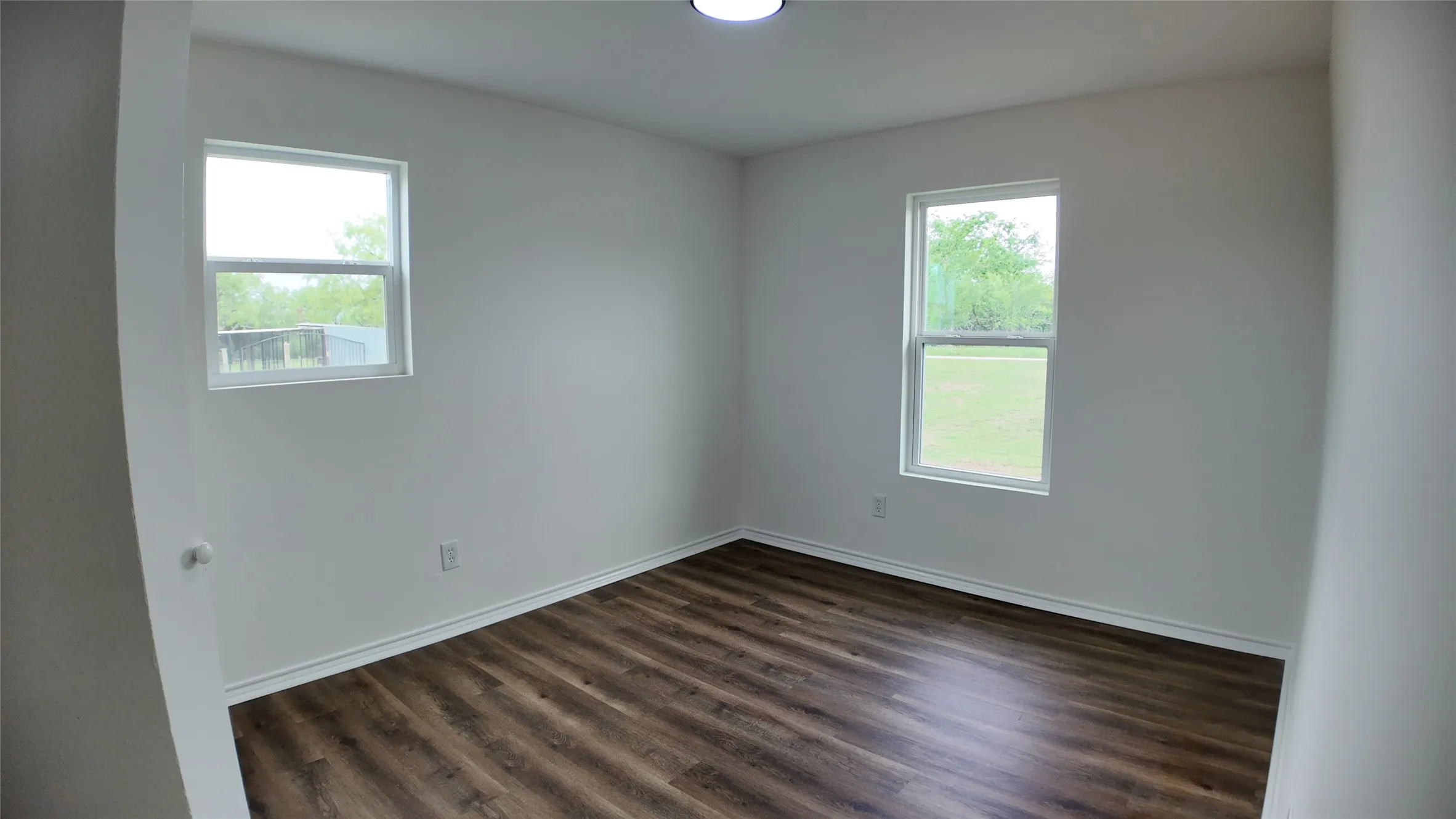 Spacious interior featuring wood-finish flooring, white baseboards, and two windows
