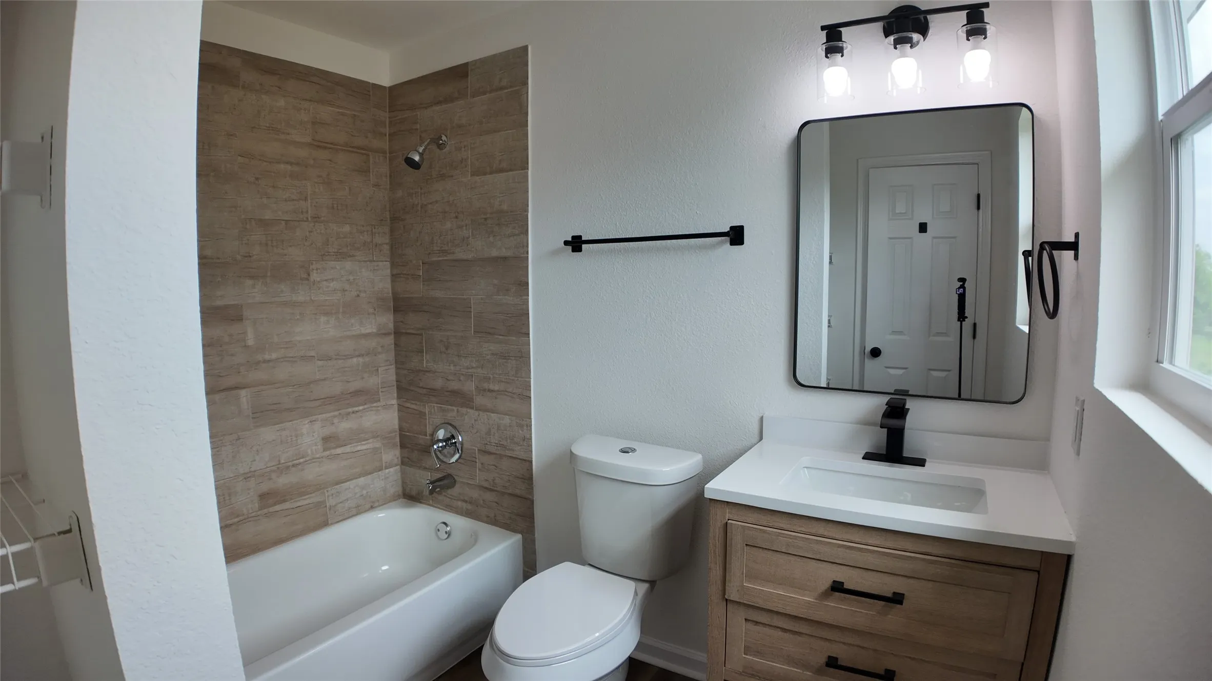 Bathroom featuring a single vanity with wood-finish cabinetry, a white countertop, and a matte black faucet