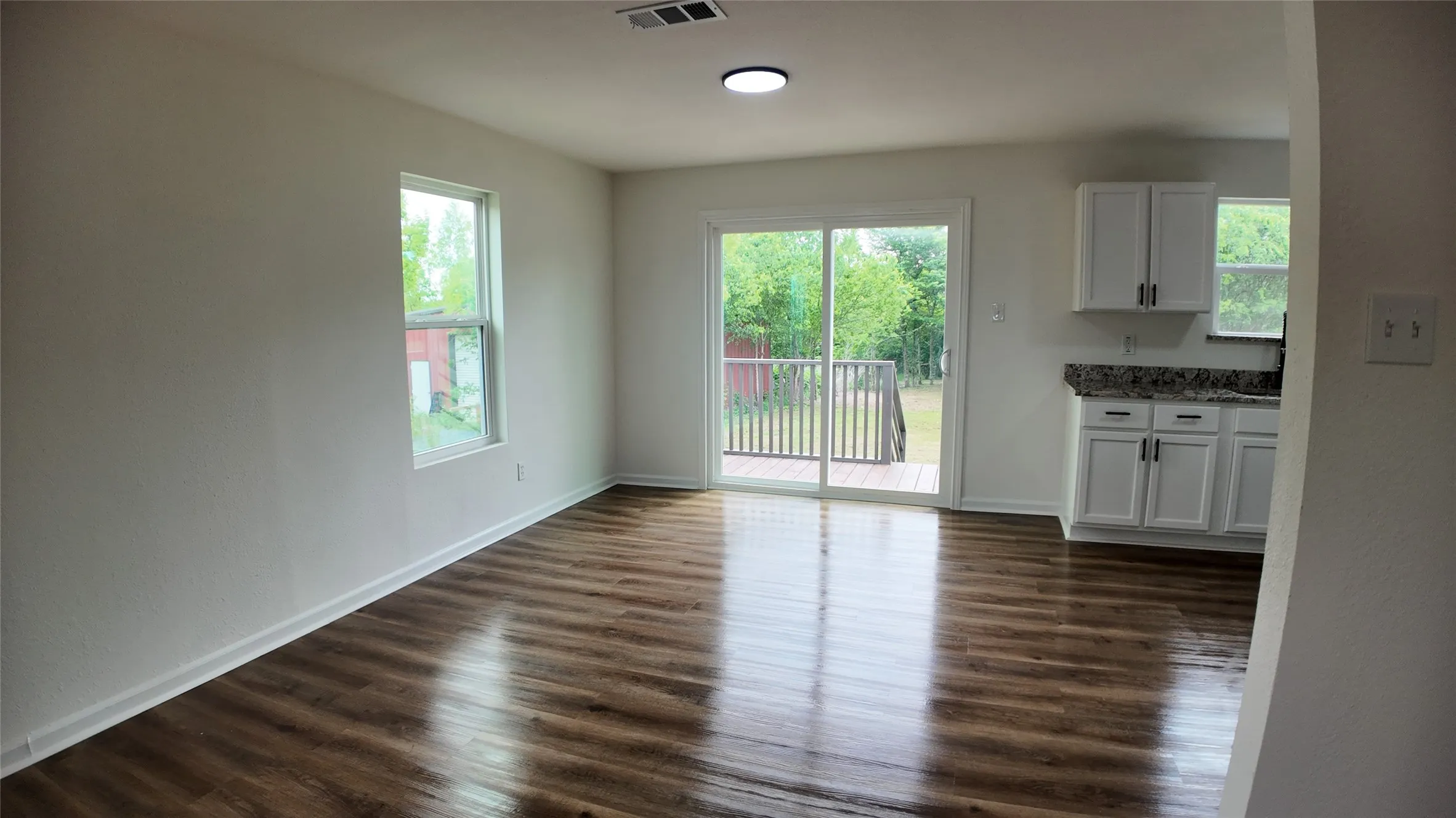 Open concept living area featuring wood-finish flooring, white walls, and a recessed ceiling light