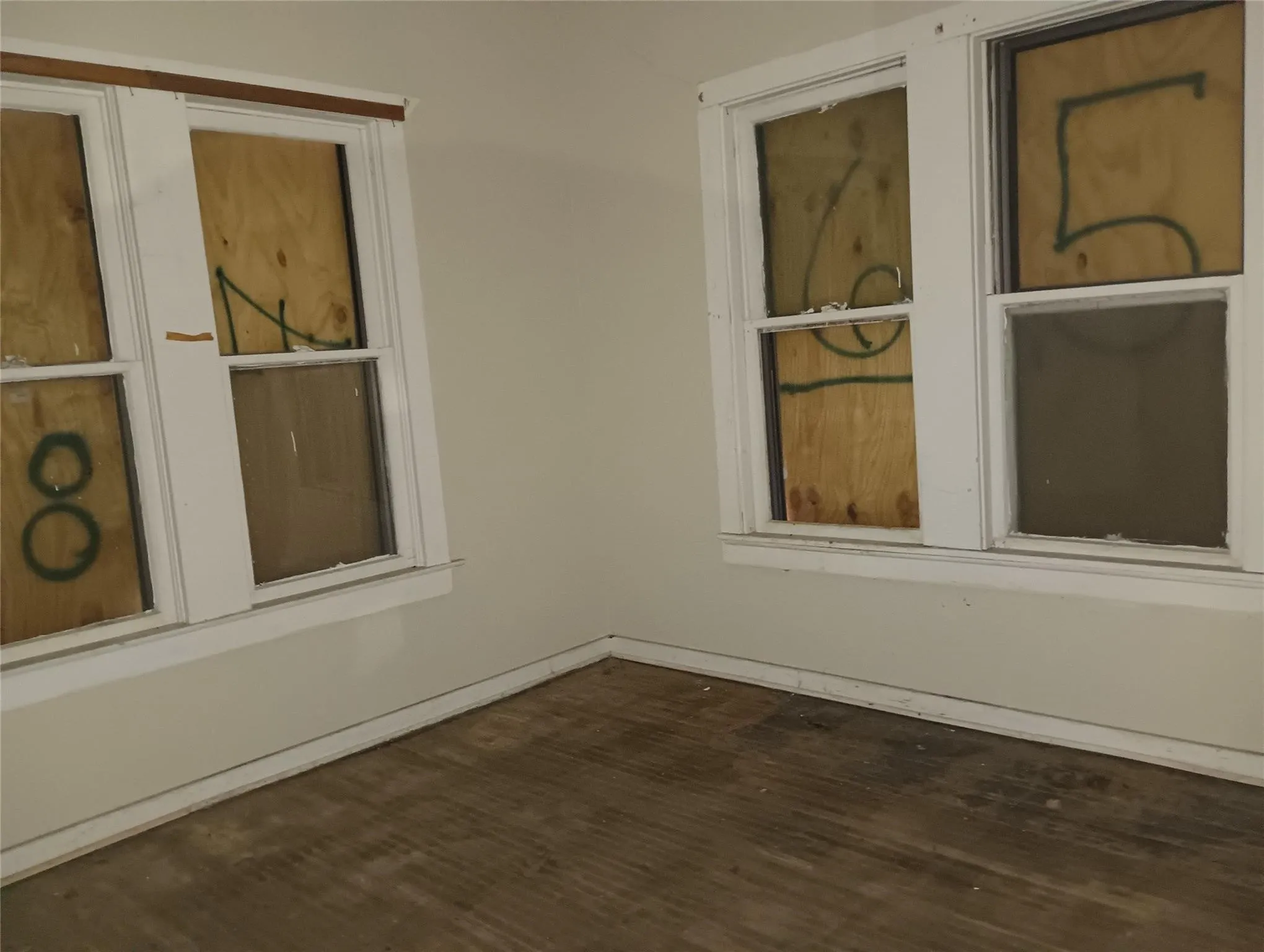 Interior space featuring two multi-pane windows with white trim and a wood-finish floor