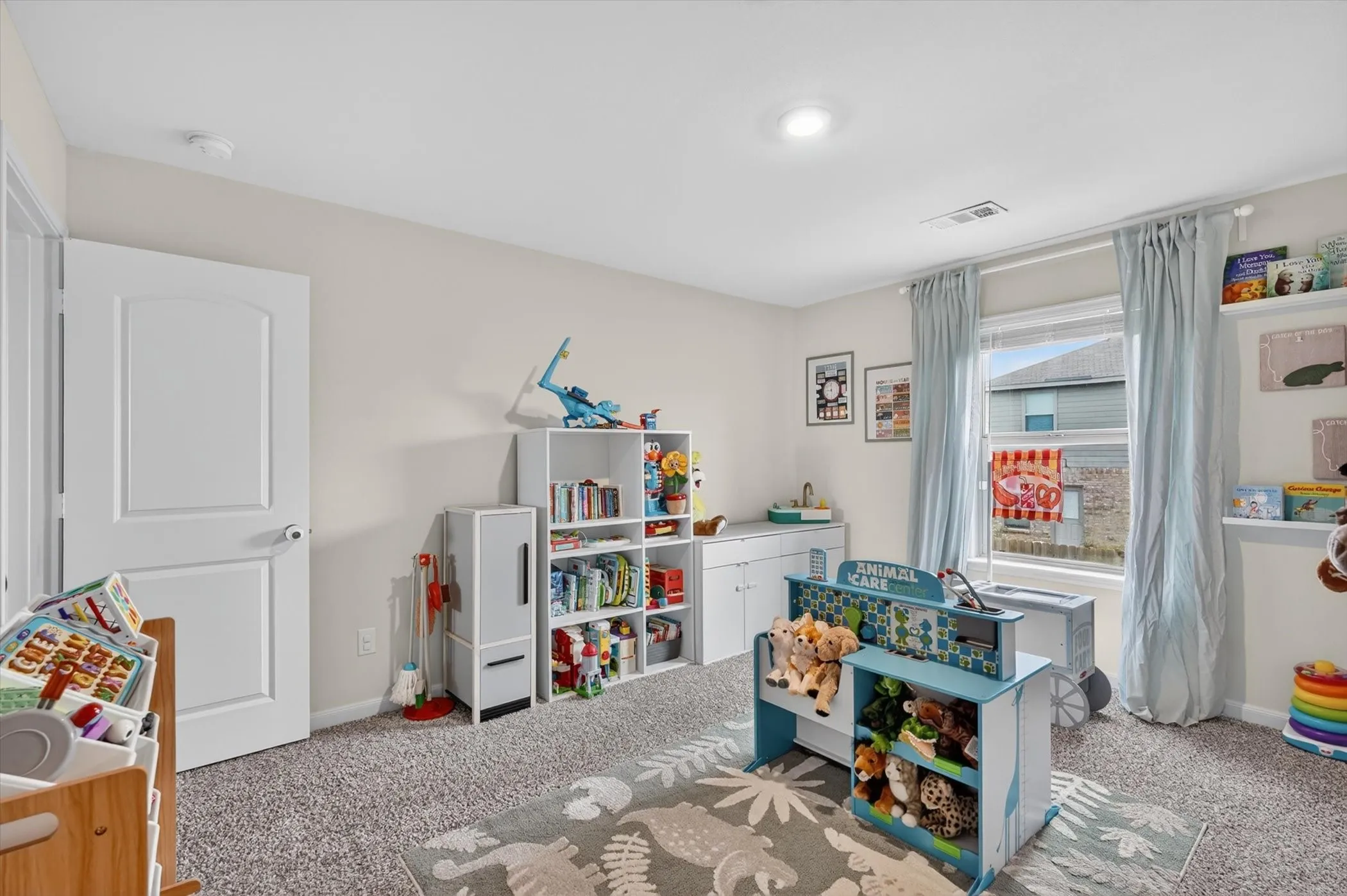 Window-equipped room featuring light gray carpeting, white walls, a white paneled door, and recessed lighting
