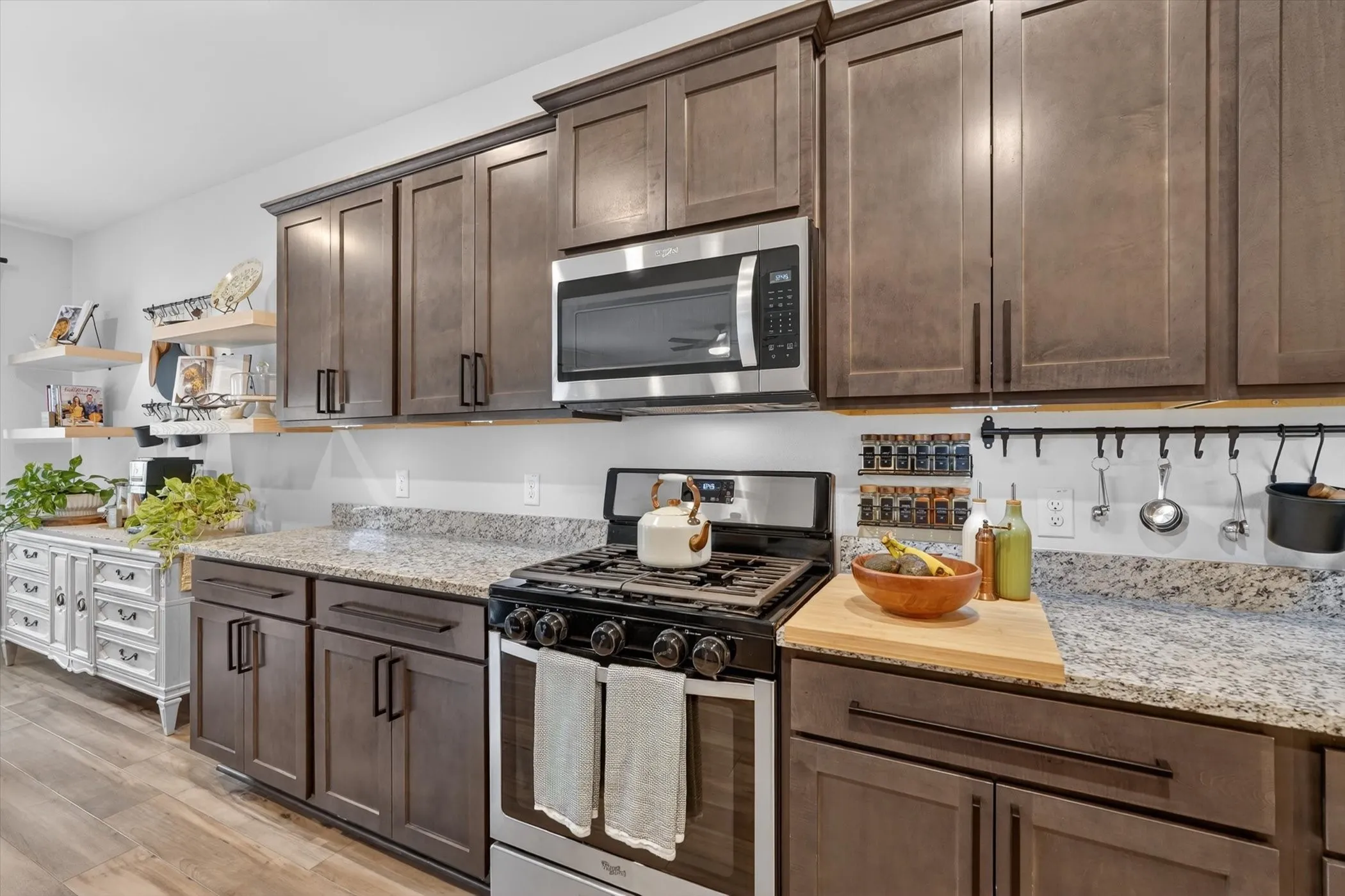 Kitchen featuring wood-finish cabinetry, stainless steel appliances, speckled countertops, and wood-finish flooring