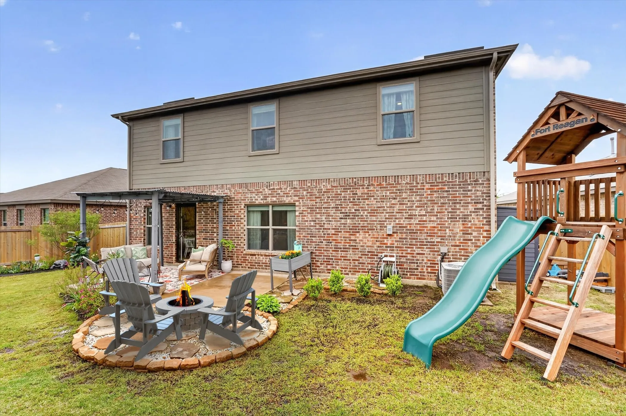 Virtual staged Firepit. Brick and siding exterior with a covered patio featuring a dark-stained pergola