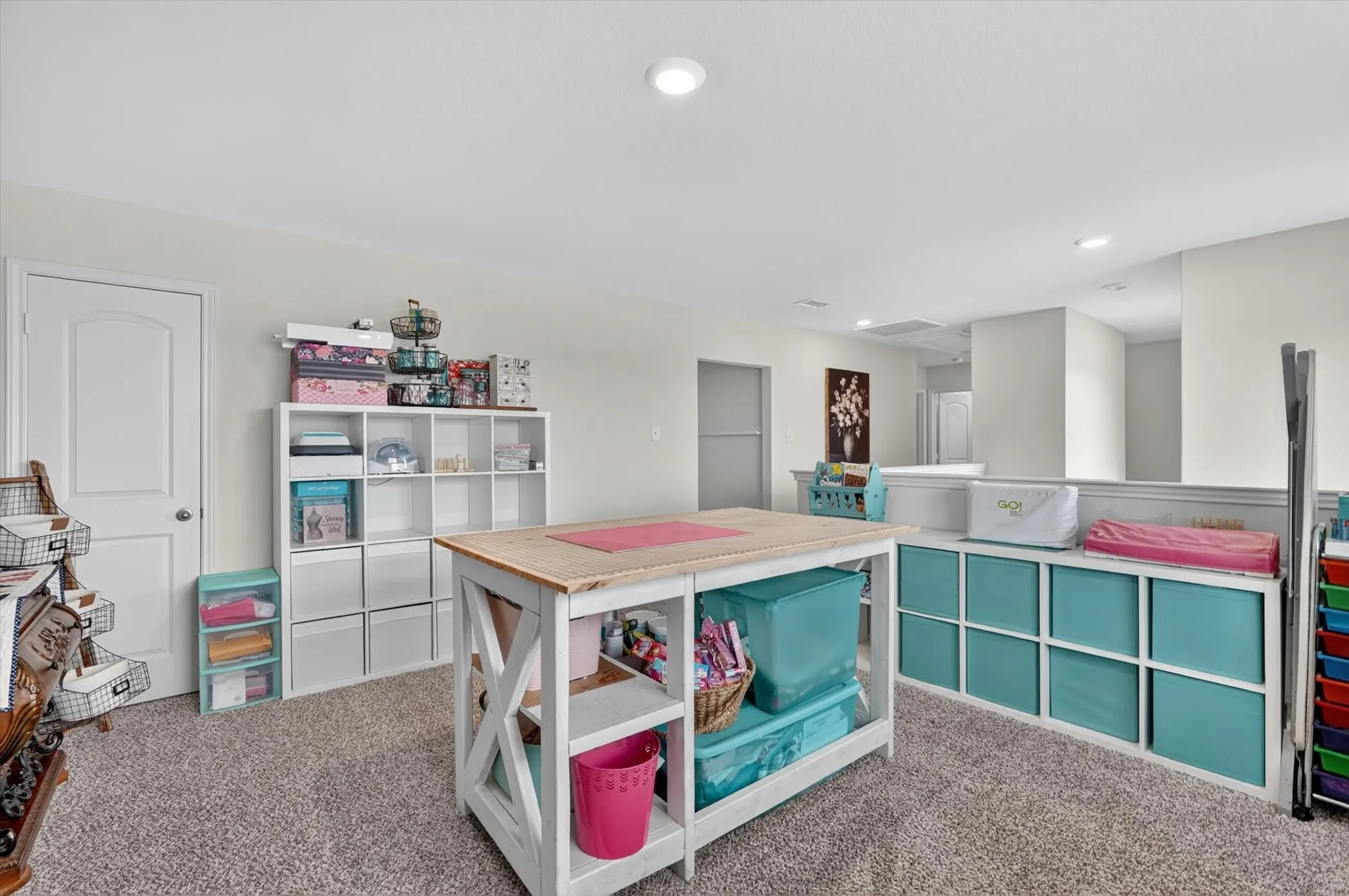 Carpeted room with recessed lighting and a white paneled door