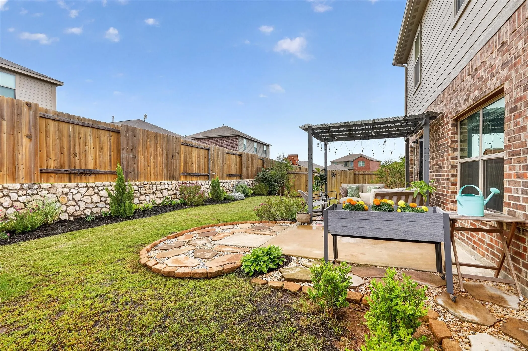 Expansive backyard featuring a stone retaining wall, manicured lawn, and a wooden privacy fence