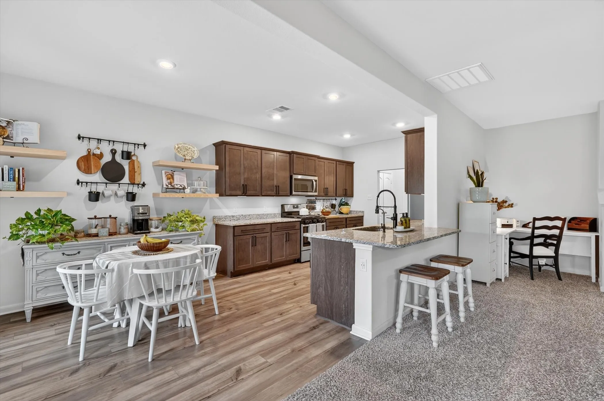 Open-concept kitchen and dining area featuring wood-finish flooring, recessed lighting, and granite countertops
