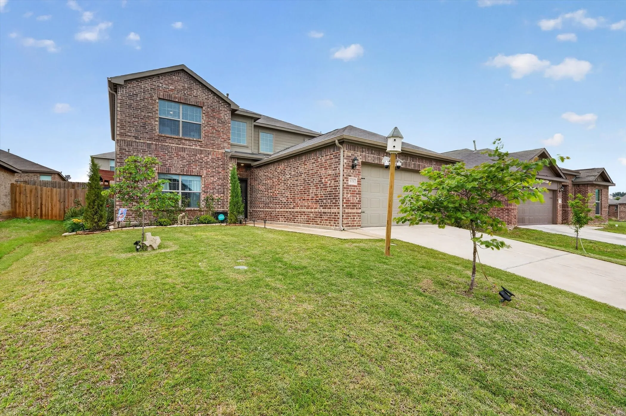 Two-story brick facade residence featuring a two-car garage, partial siding accents, and a concrete driveway
