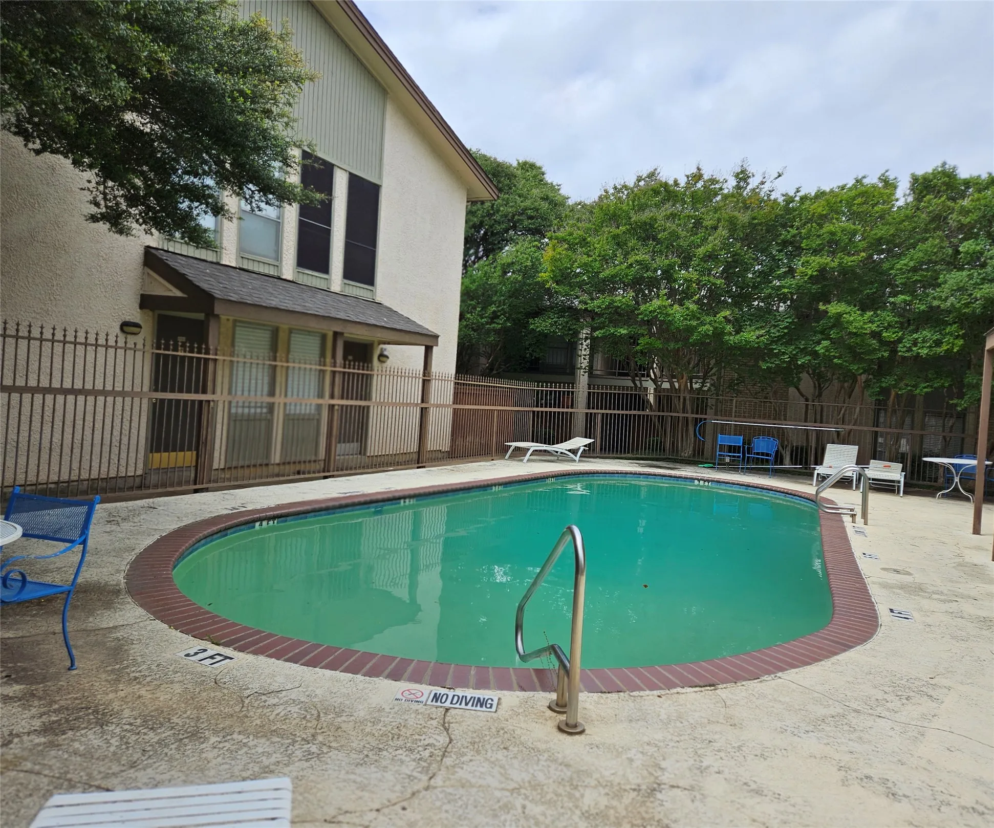 Curved swimming pool with a brick coping and concrete decking