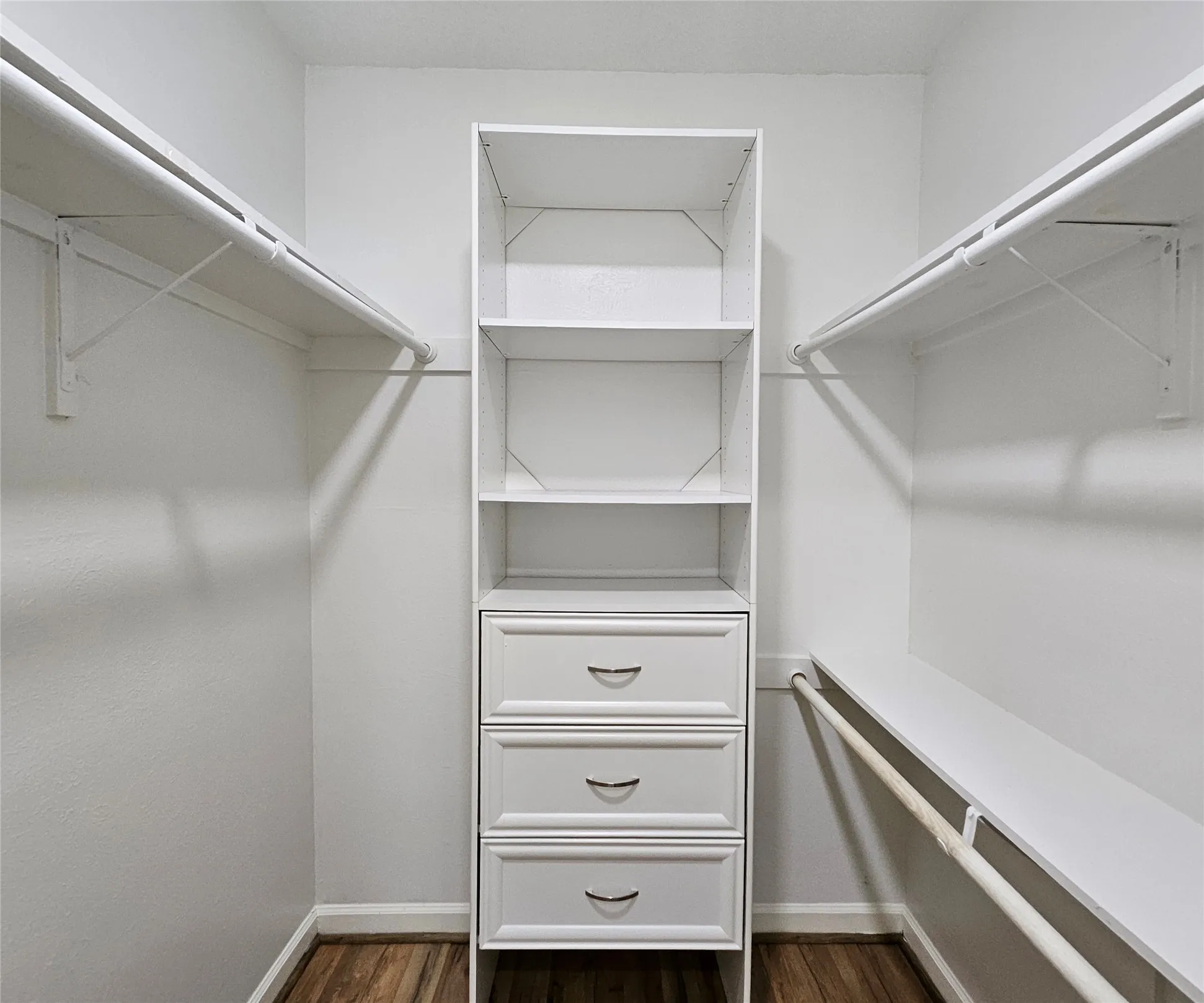 Walk-in closet featuring built-in shelving, three drawers with curved