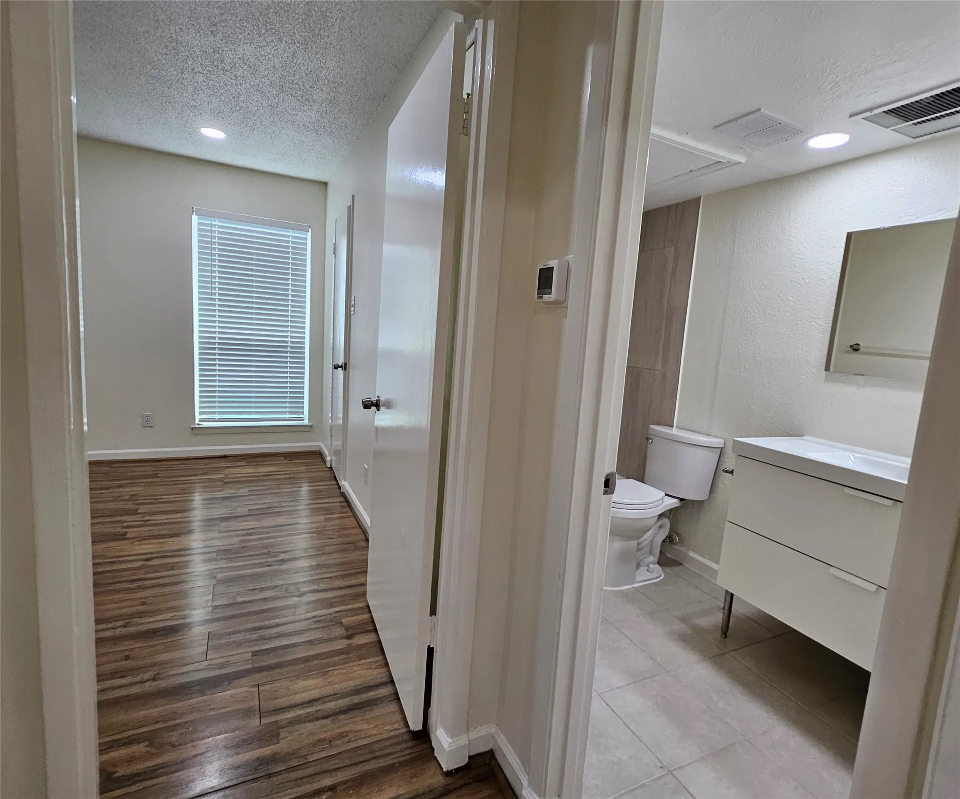 Bedroom featuring wood-finish flooring, recessed lighting, and a window with blinds