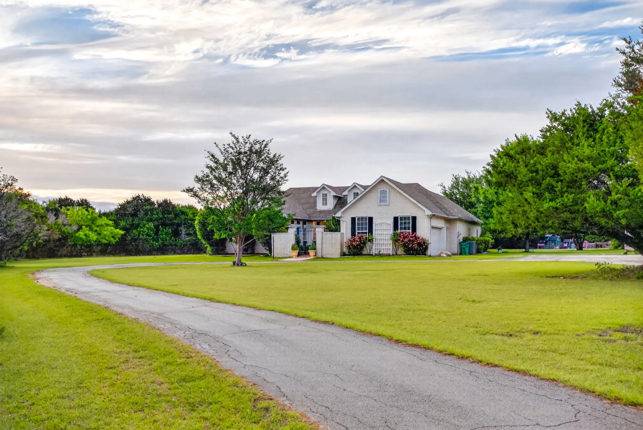 Long circle drive leading to the garage (with EV charging station), extra parking pad, and well house.