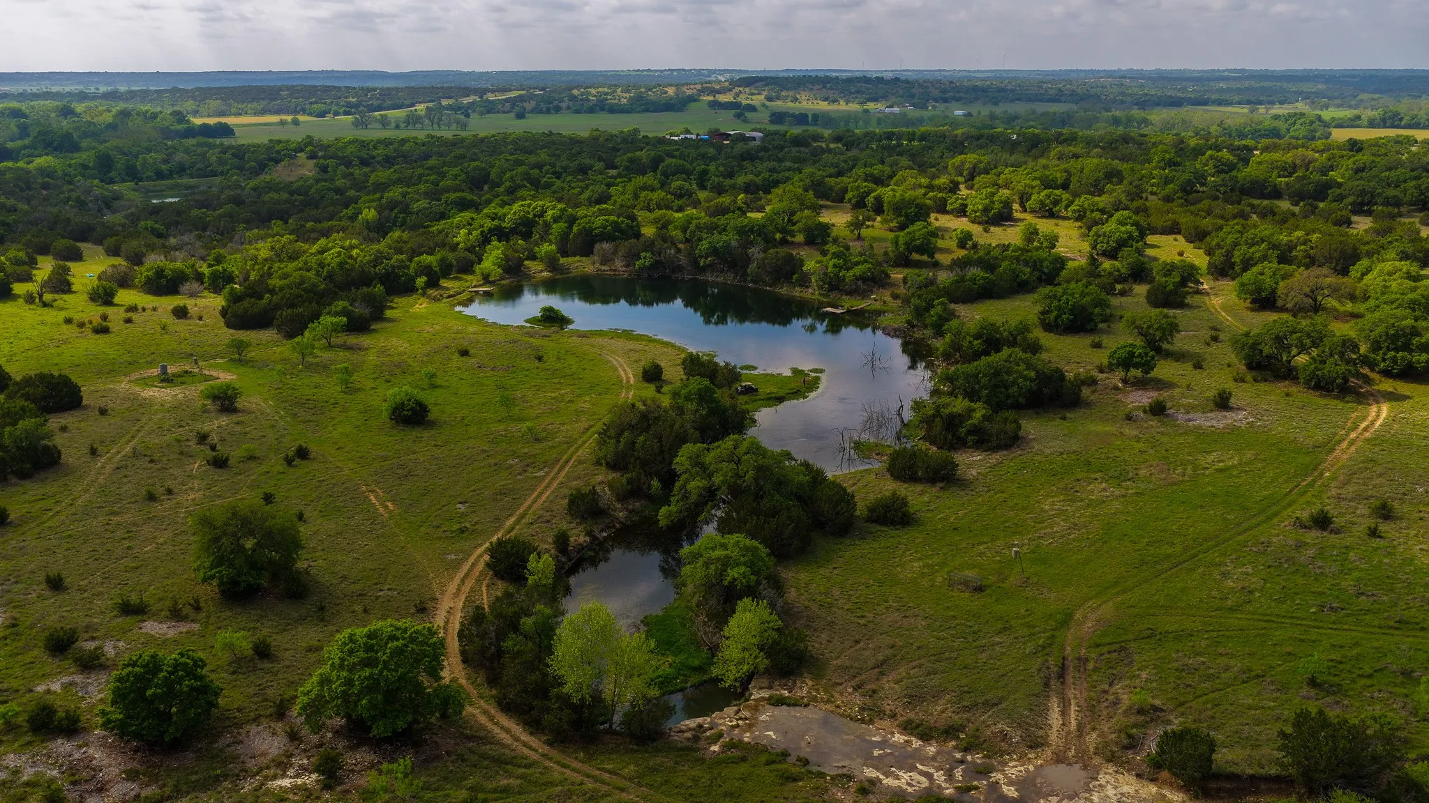 Expansive acreage featuring multiple bodies of water, verdant trees, and natural clearings
