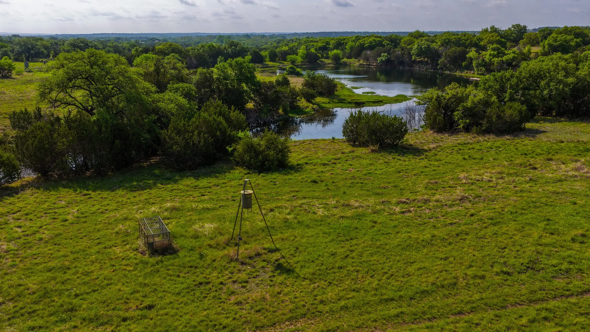 Expansive green acreage featuring a natural water body and abundant mature trees